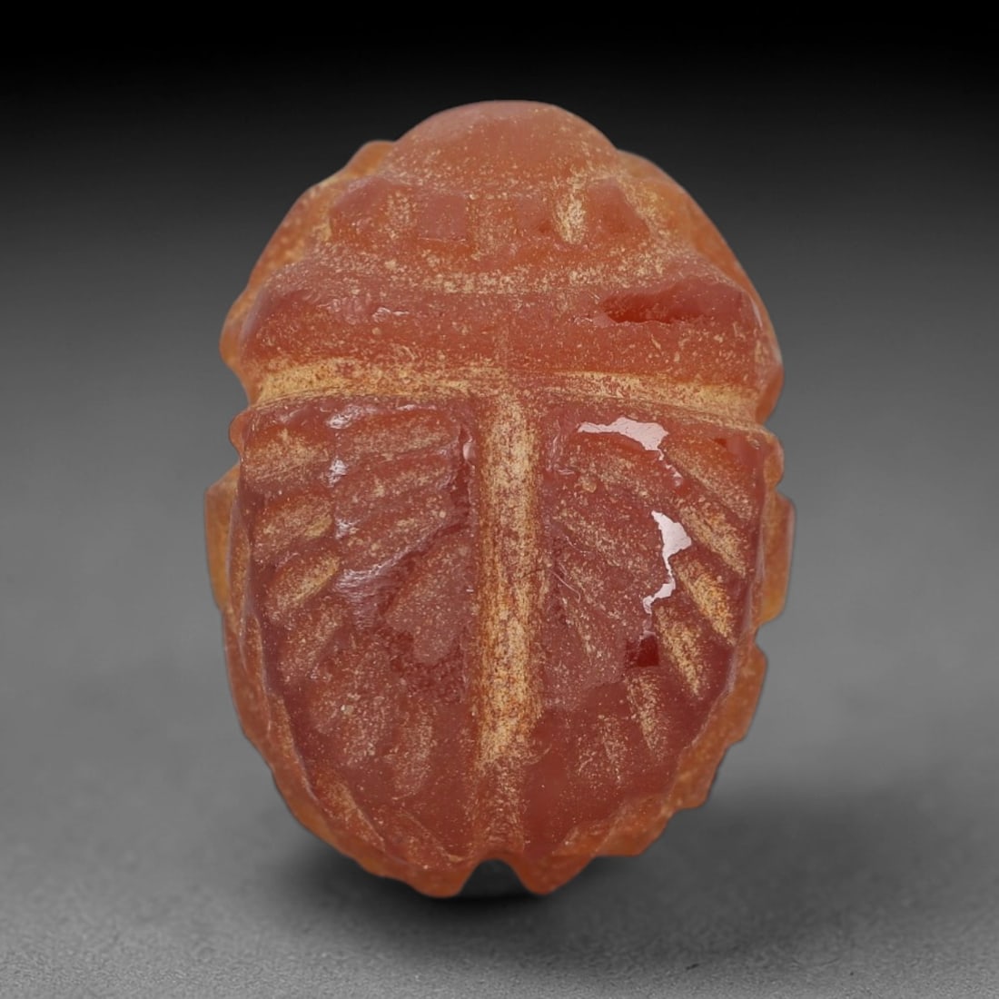 Ancient Carnelian Scarab Amulet - Egyptian Figurine, 39XS: Carved from warm, translucent orange-red carnelian with natural tonal gradients and subtle internal veining, this amulet is formed as a stylized scarab beetle with incised linear detailing to define t