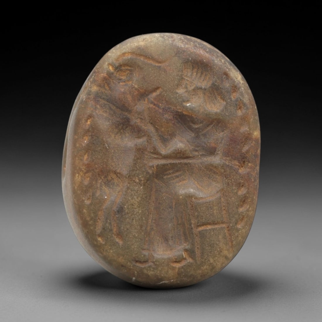 Ancient Near Eastern Stone Stamp Seal - Figural Amulet, 31ZR: This artifact is a carved stone stamp seal amulet, crafted from a dense, earthy-brown stone with a smooth, weathered surface and natural patina filling the incised details. The oval seal face depicts
