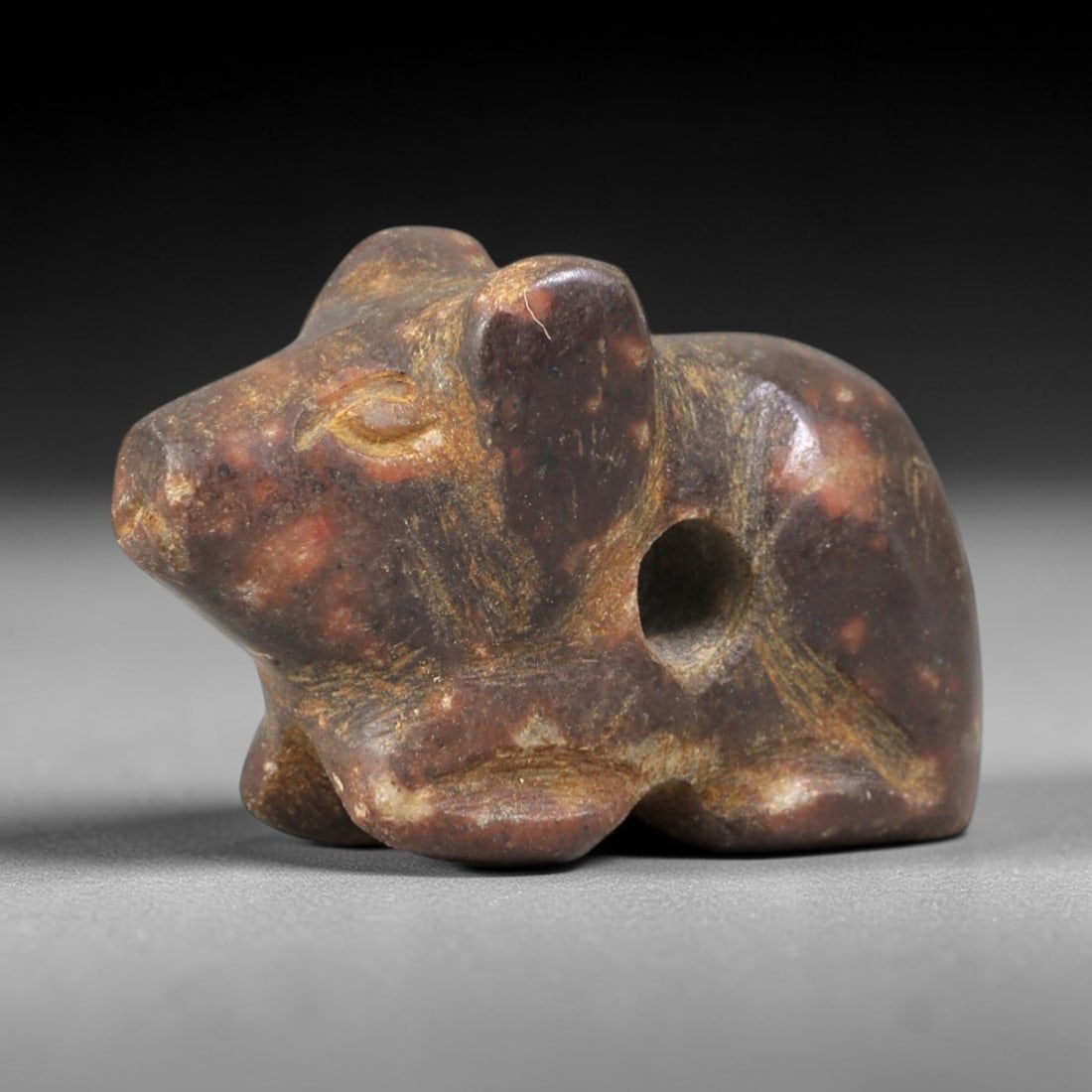 Ancient Stone Rodent - Near Eastern Amulet Figurine, 26AS: Carved from speckled hardstone, this amulet depicts a compact, crouching rodent form with stylized features. The head is rounded with incised eye motifs, a defined snout, and large upright ears, while