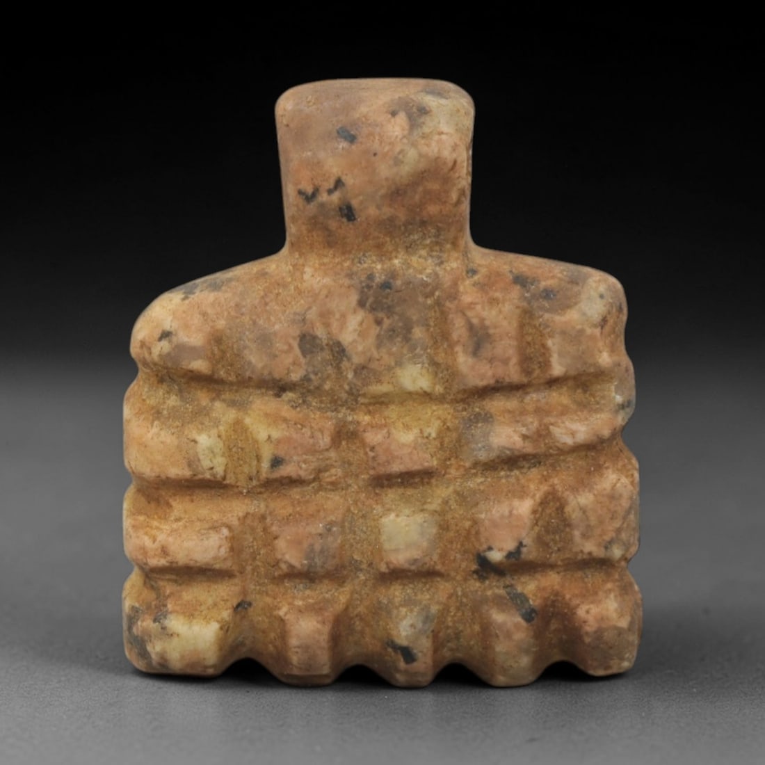 Ancient Stone Idol - Near Eastern Anthropomorphic Figure, 86XQ: Carved from a speckled, tan-brown stone, this idol presents a stylized anthropomorphic form with a blocky head, broad shoulders, and a torso segmented by horizontal and vertical incisions into a grid-