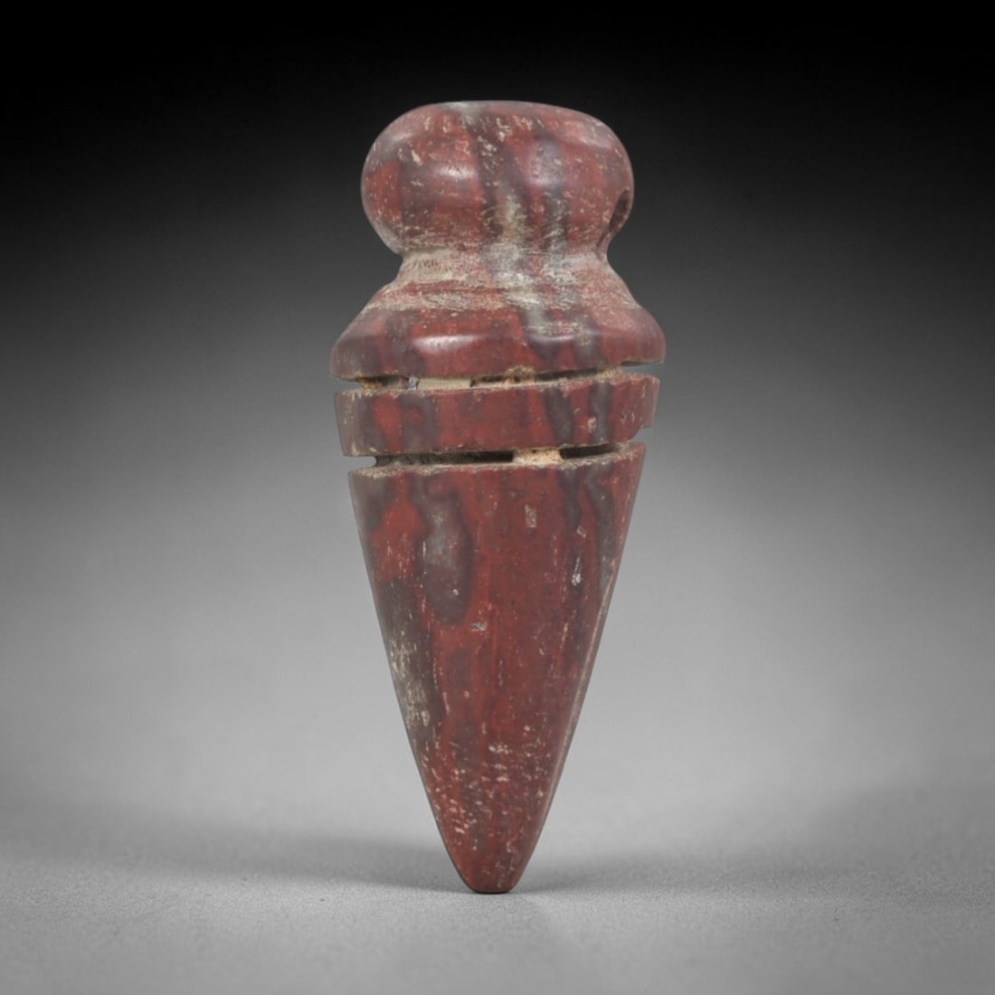 Ancient Stone Amulet - Egyptian Ritual Pendant, 78AP: This artifact is carved from variegated red stone with a weathered, earthy patina and natural mineral veining, exhibiting precise incised linear detailing consistent with ancient Egyptian stoneworking