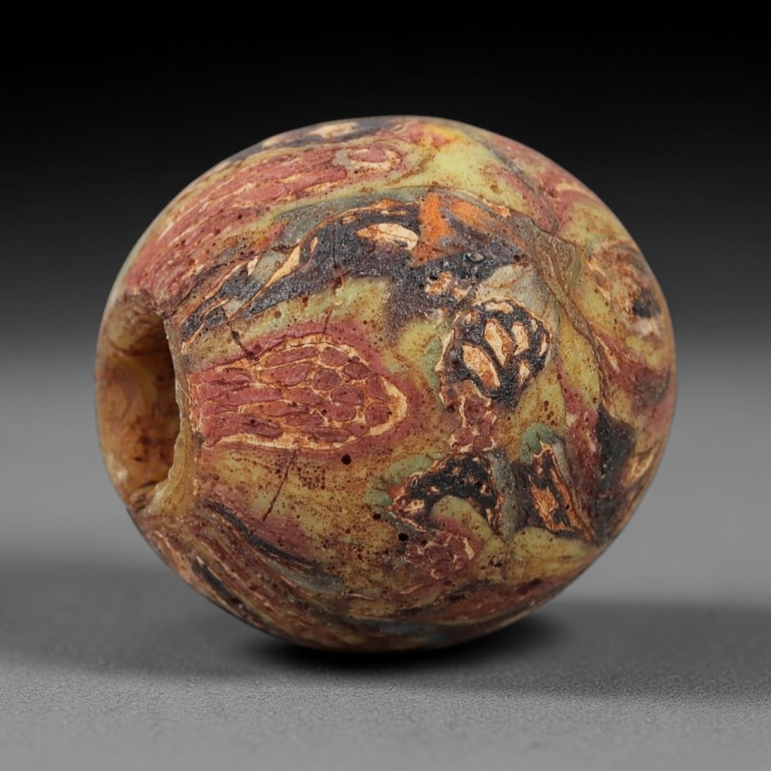 Ancient Islamic Glass Bead - Patchwork Mosaic Amulet Bead, 11FW: This spherical bead is crafted from layered mosaic glass, featuring a rich patchwork of earthy tones-olive green, deep red, black, and amber-with organic, textured inlays characteristic of medieval Is