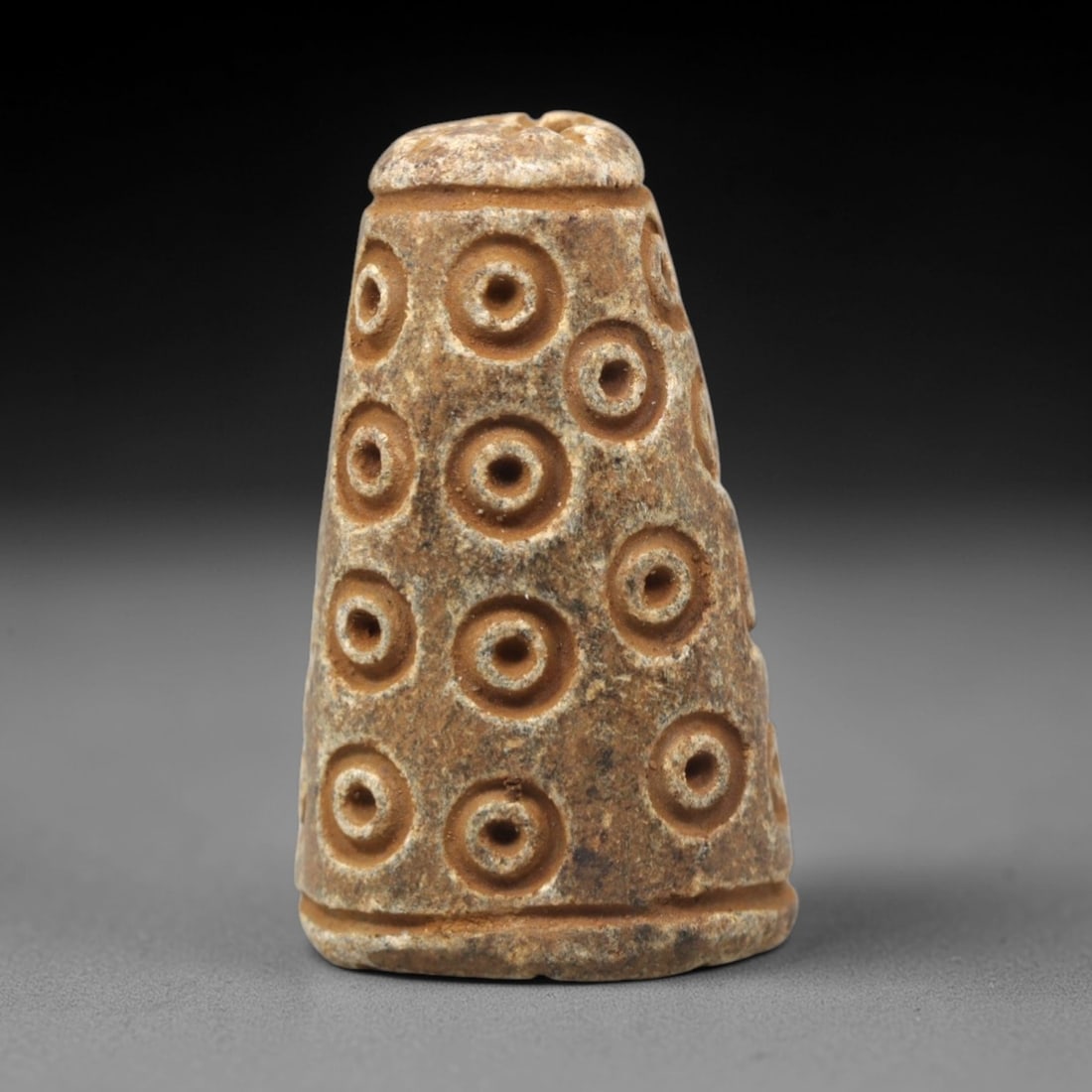 Ancient Steatite Amulet - Near Eastern Concentric Circles, 53XV: Carved from dense steatite, this ancient amulet features a tapered conical form with a small suspension hole at the top, designed for wearable use. Its surface is decorated with multiple vertical rows