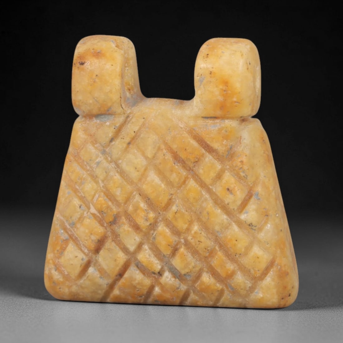 Ancient Stone Amulet - Near Eastern Carved Pendant, 58AR: This artifact is carved from a warm, golden-hued stone with subtle orange and cream tonal variations, exhibiting a smooth, aged patina and faint mineral inclusions. The form is a compact, trapezoidal
