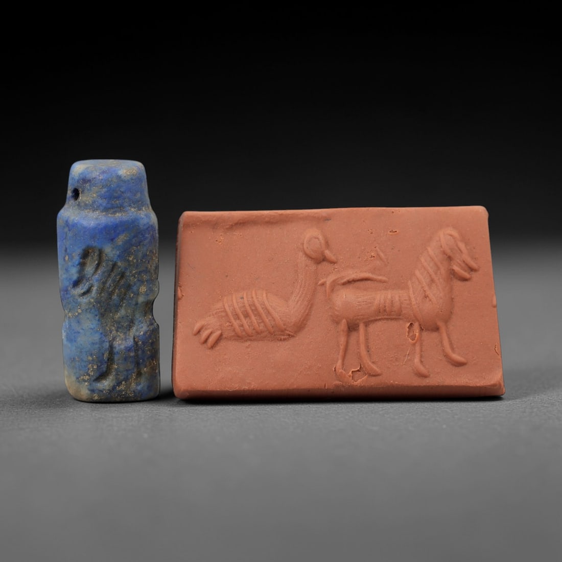Ancient Near Eastern Lapis Lazuli Cylinder Seal - Bird & Horse Motif, 62AH: Carved from lapis lazuli, this small cylinder seal features incised depictions of a bird and horse, a motif common in ancient Near Eastern glyptic art. The piece exhibits a natural deep blue patina wi