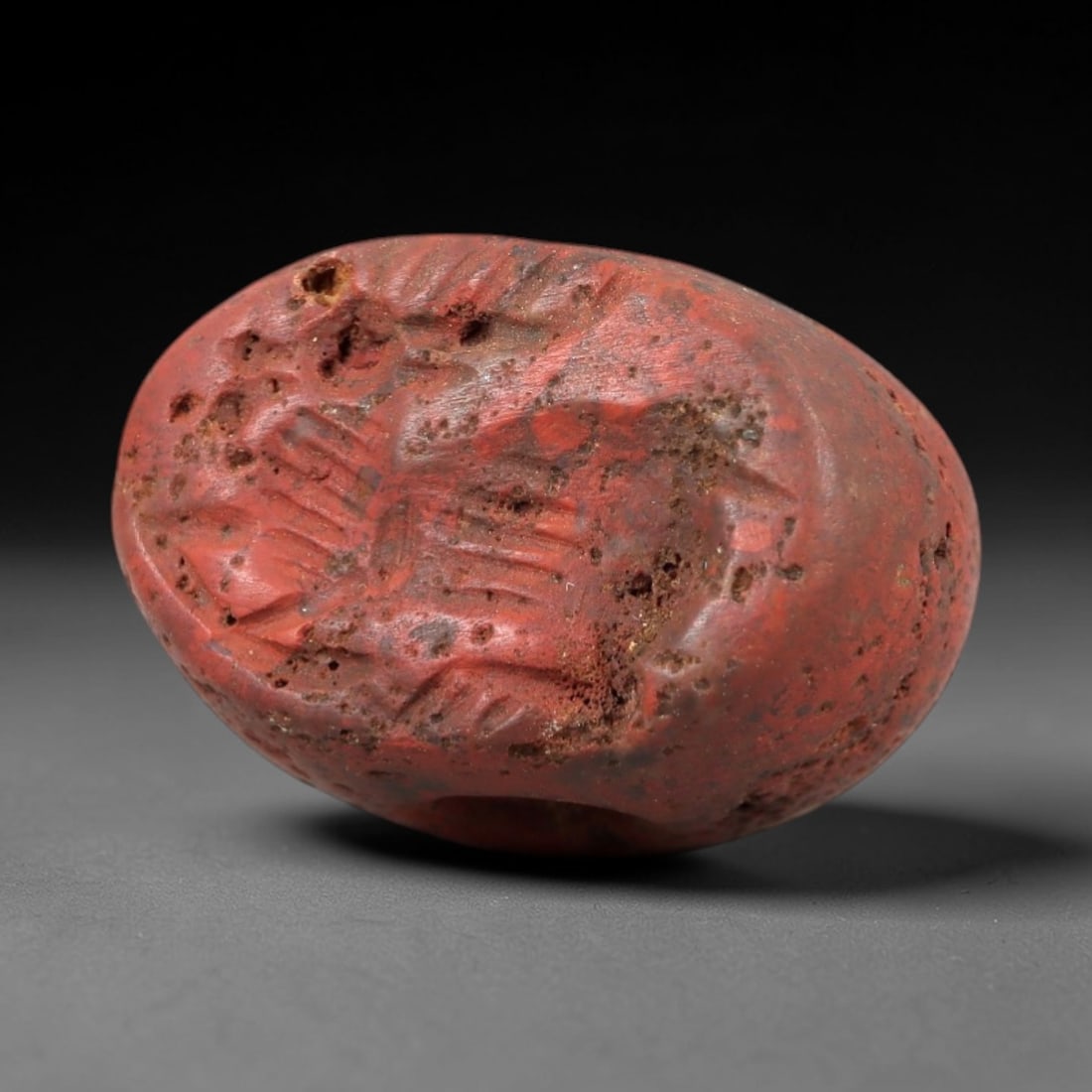 Ancient Jasper Stamp Seal - Near Eastern Gazelle Figure, 89AM: Carved from porous red jasper, this hemispherical stamp seal depicts a stylized gazelle with linear incised details defining its body, limbs, and horn structure. The iconography reflects the animal-ce