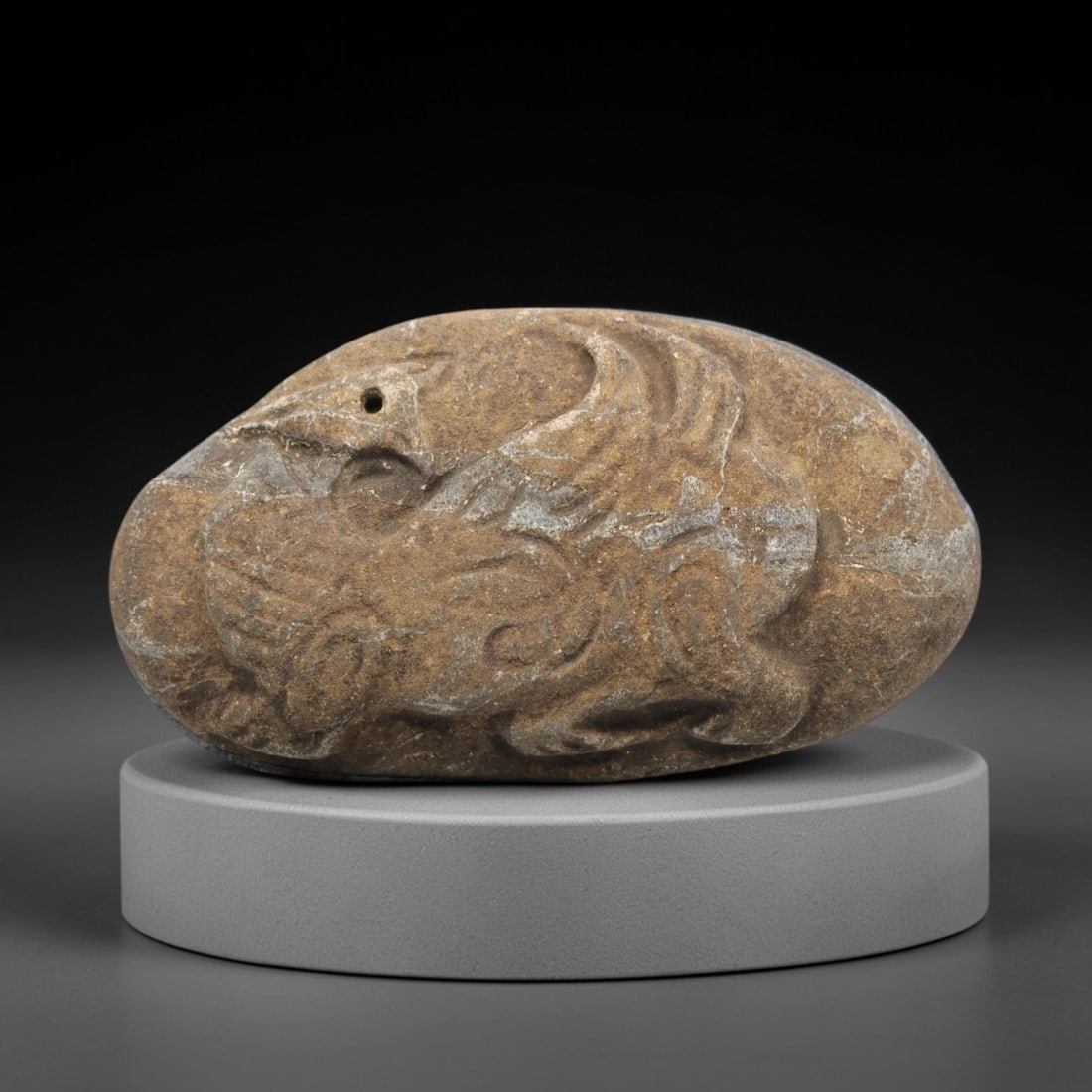Ancient Stone Bird Amulet - Near Eastern Christian Figurine, 87ZV: Carved from a naturally rounded stone, this amulet features a relief depiction of a bird in dynamic pose, with incised details defining its wings, body, and facial features. A small suspension hole is