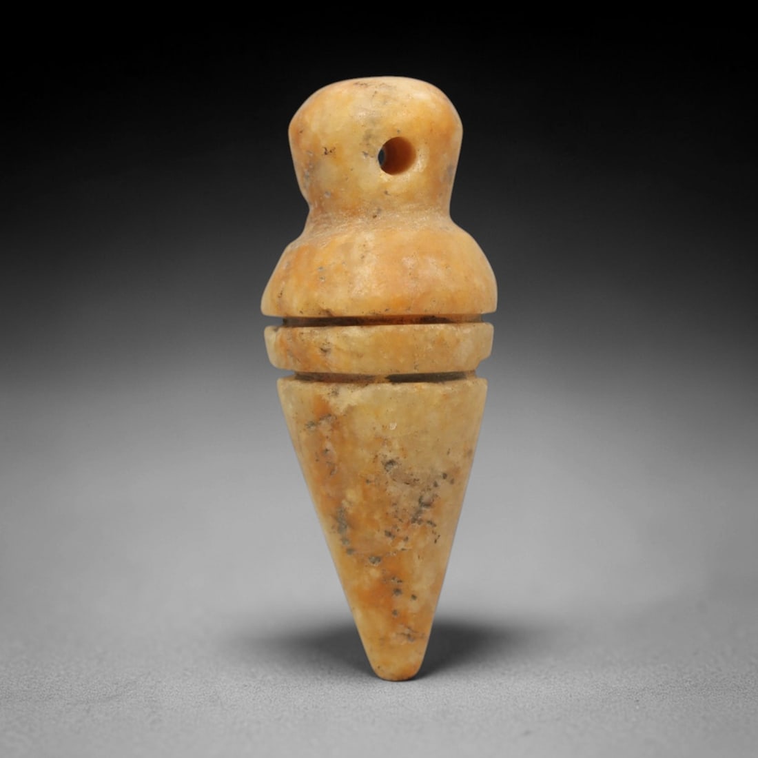 Ancient Calcite Conical Amulet - Near Eastern Ritual Pendant, 42ZW: This amulet is carved from warm orange-brown calcite, featuring a symmetrical conical form with a rounded top, a perforated suspension bead, and two horizontal incised rings dividing the upper and low