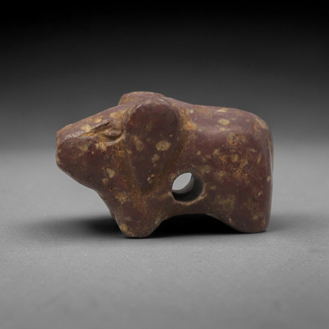Ancient Stone Rodent Amulet - Near Eastern Figurine, 94XV: This amulet is carved from a mottled reddish-purple stone with natural earthy inclusions and a weathered patina across its surface, executed in a simplified, blocky manner that emphasizes the compact