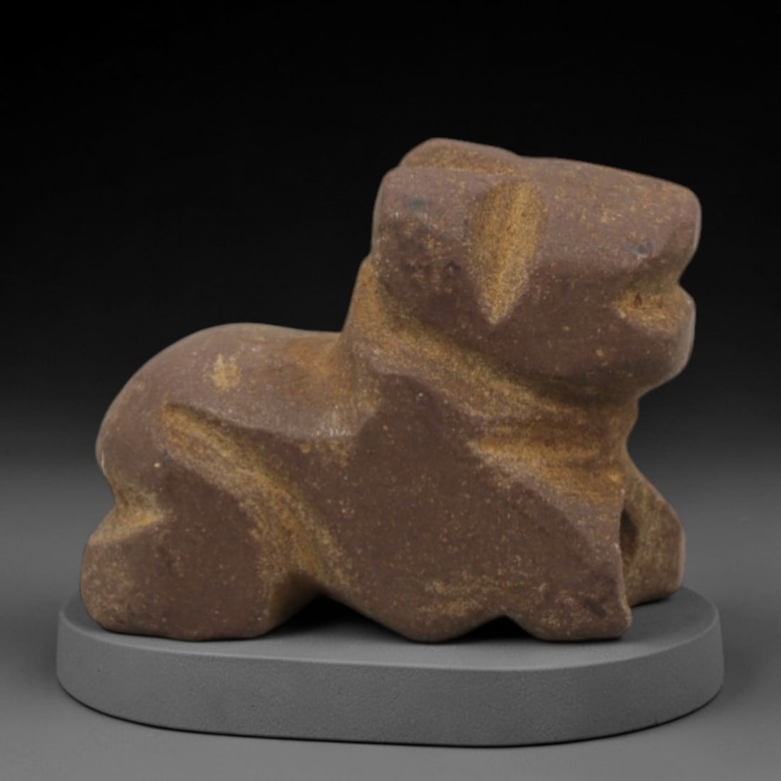 Ancient Stone Zoomorphic Amulet - Near Eastern Figurine, 67XQ: Carved from a rich reddish-brown stone with natural earthy patination, this amulet depicts a stylized recumbent zoomorphic form, likely a canine or bovid, with a blocky head, thick neck, and compact,