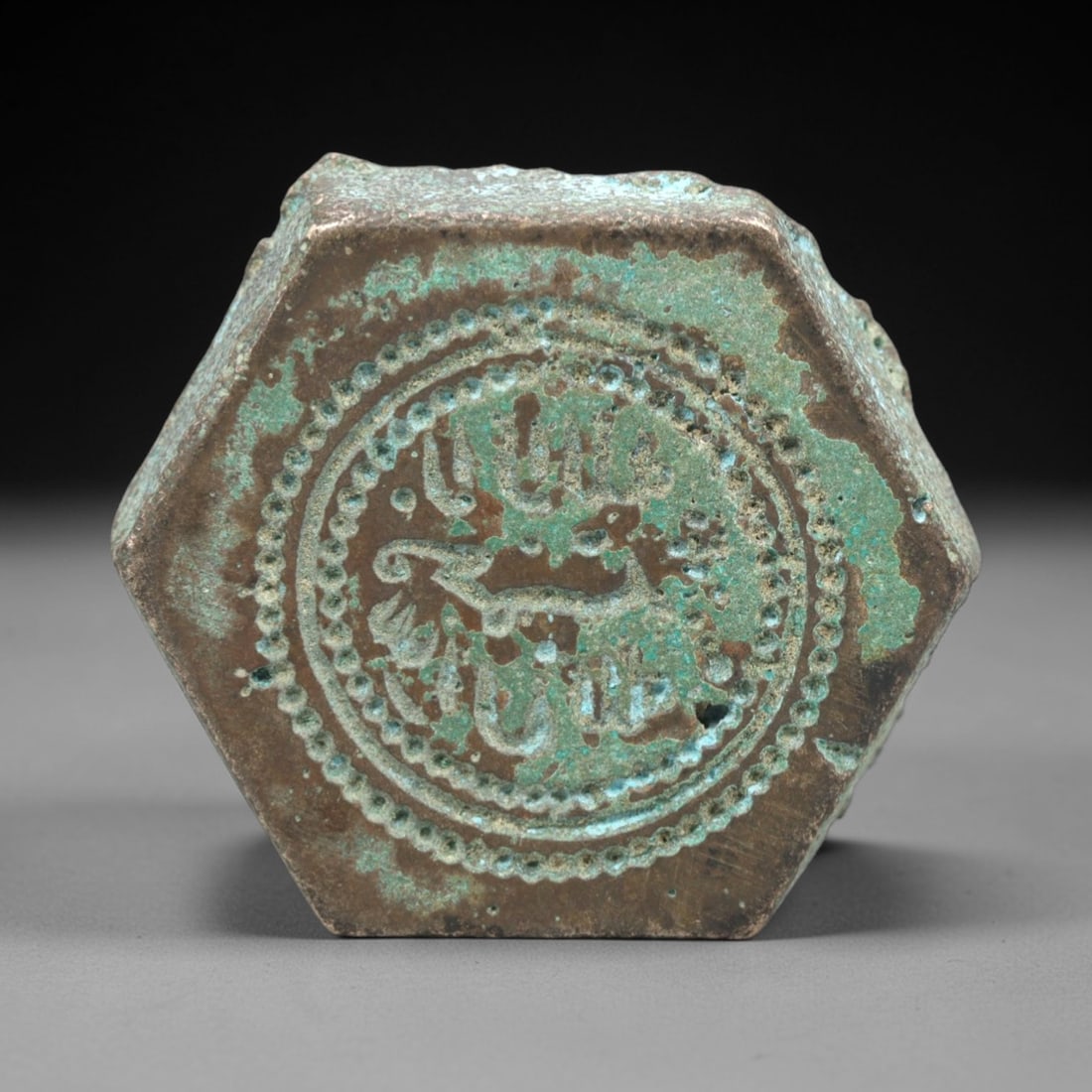 Ancient Islamic Bronze Weight - Hexagonal Administrative Artifact, 86ZP: This artifact is a hexagonal Islamic bronze weight, executed in the utilitarian decorative tradition of medieval Islamic culture. The face features a circular border of raised beaded dots, enclosing i
