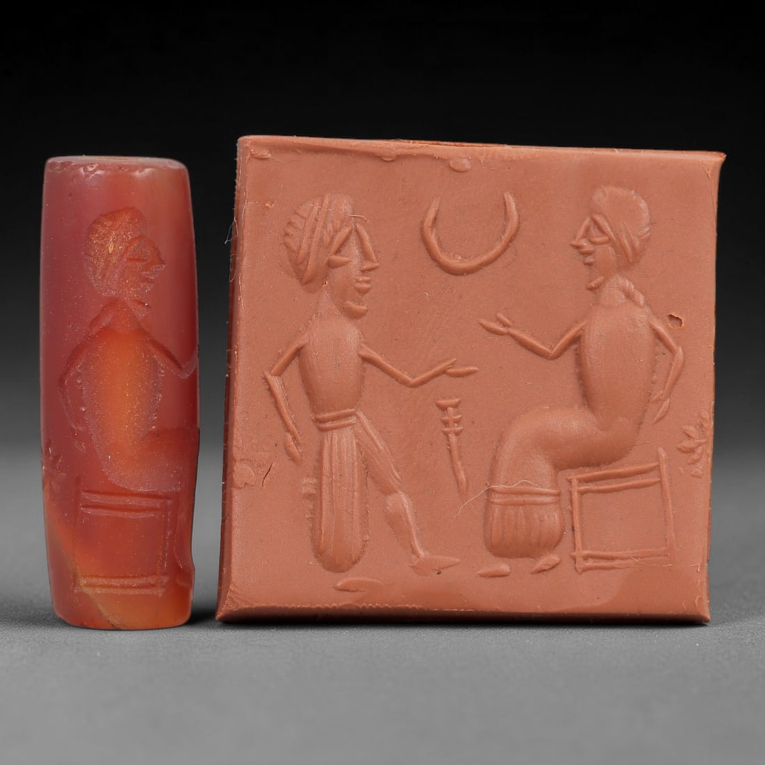 Ancient Carnelian Cylinder Seal - Mesopotamian Figural Dialogue Scene, 57AN: Carved from warm-hued carnelian, this ancient Mesopotamian cylinder seal features a refined linear relief composition of two human figures in dialogue-one standing and gesturing, the other seated on a