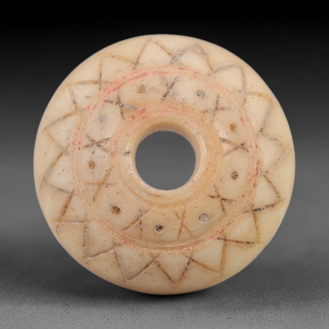 Ancient Bone Spindle Whorl - Near Eastern Crosshatched Motif, 67XR: This ancient Near Eastern spindle whorl is carved from bone, featuring a biconvex form with a central perforation. The surface is decorated with incised crosshatched and circular motifs, a common deco
