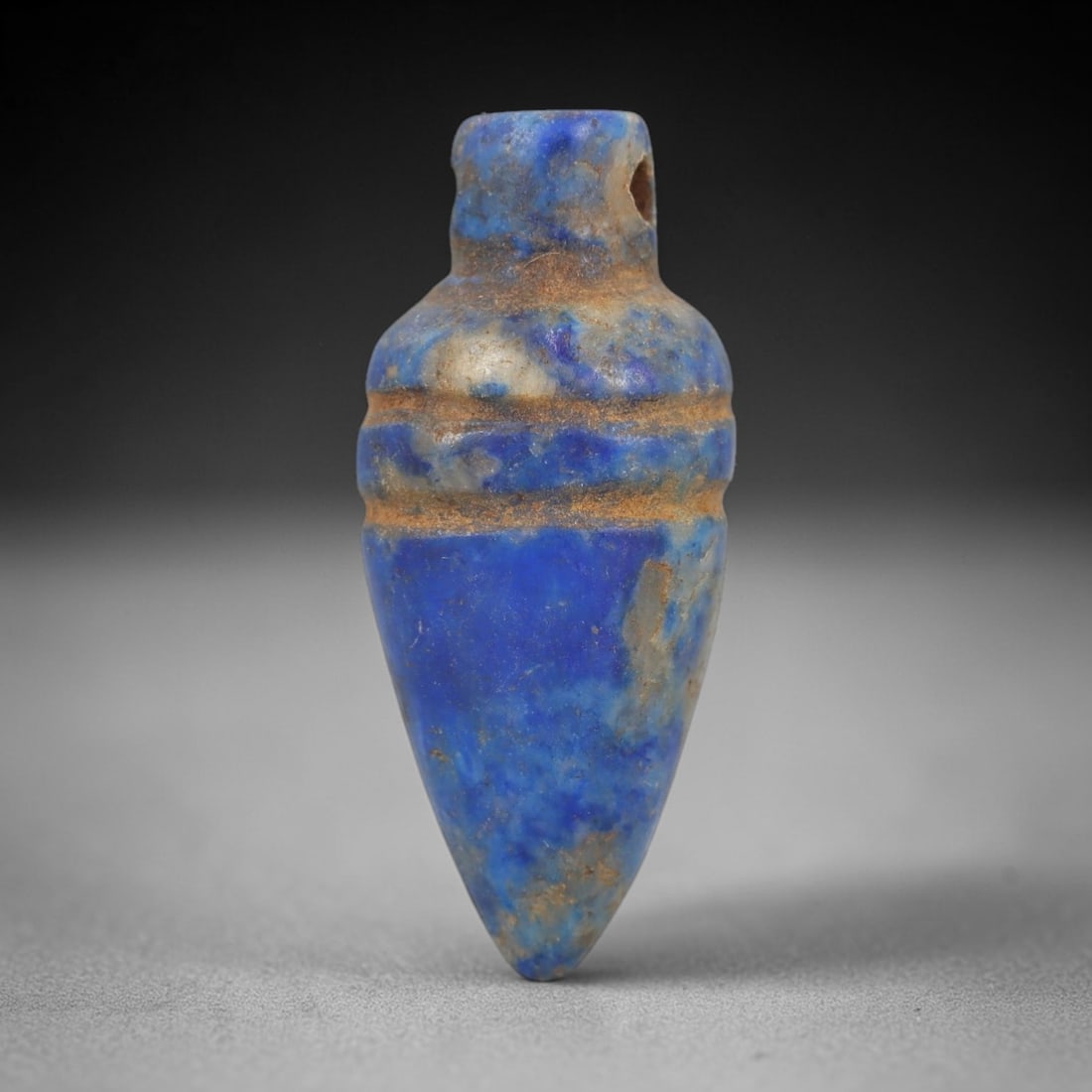 Ancient Lapis Lazuli Heart Amulet - Egyptian Ritual Pendant, 9AP: Carved from lapis lazuli, this amulet is formed in a tapering heart-like shape, with a cylindrical upper lug pierced for suspension, its body marked by two incised horizontal bands that define its seg