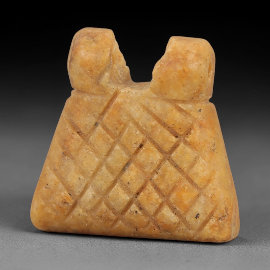 Ancient Egyptian Stone Amulet - Carved Ritual Pendant, 73AE: Carved from beige stone, this amulet features a geometric grid pattern with a suspension loop at the top, consistent with ancient Egyptian ritual pendants of the Late Period. The form is designed for