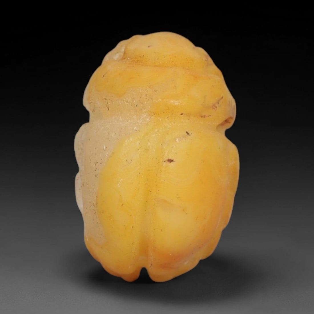 Ancient Yellow Agate Scarab Amulet - Egyptian Figurine, 60AJ: Carved from warm yellow banded agate with natural translucent inclusions, this amulet is formed as a stylized scarab beetle with subtle linear detailing to define segmented wing cases and body contour