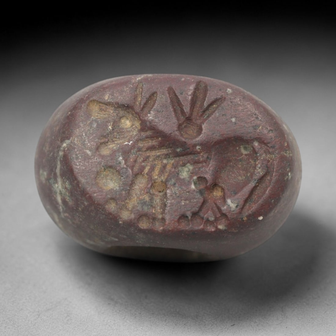 Ancient Stone Hemispherical Stamp Seal - Near Eastern Animal Pair Figure, 93ZS: Crafted from dense, reddish-brown stone, this hemispherical stamp seal bears incised carving of two stylized animal figures, likely a donkey and a hare, with linear body detailing, ear motifs, and cir