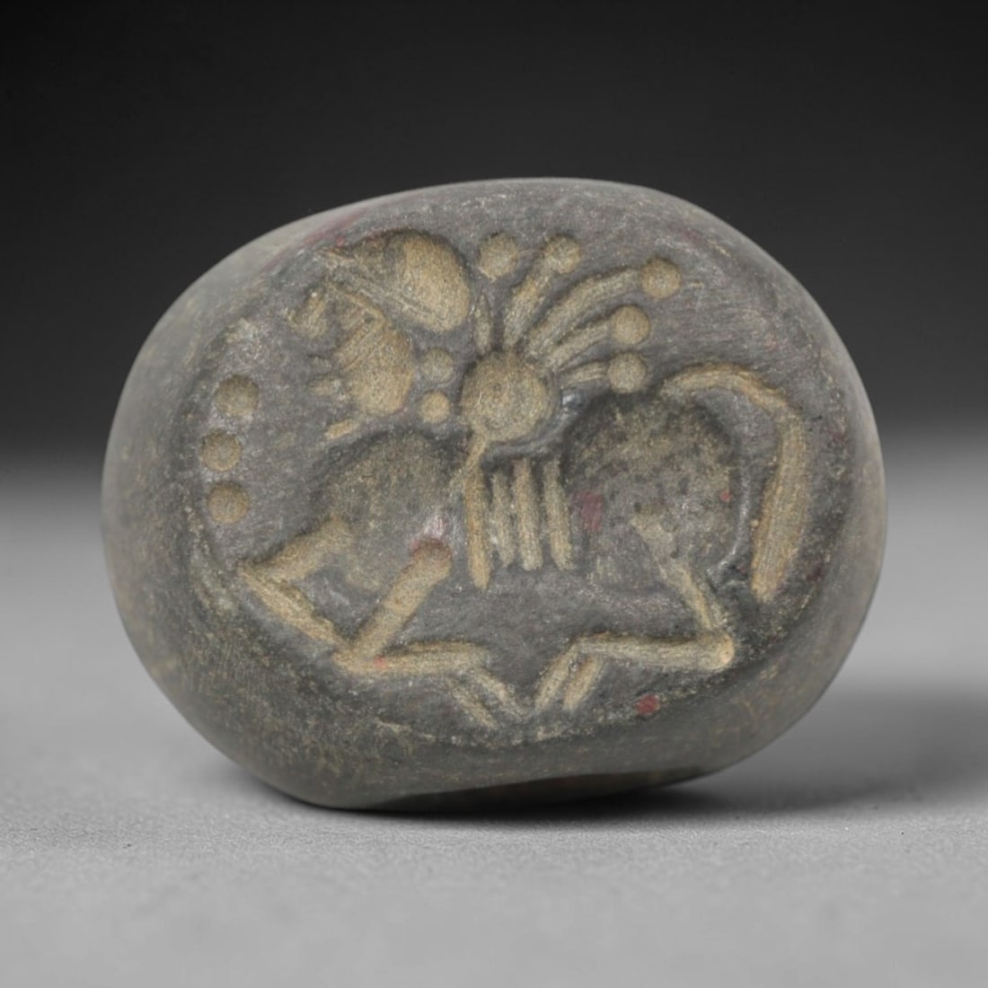 Ancient Stone Hemispherical Stamp Seal - Near Eastern Mythical Creature Figure, 85ZS: Crafted from dense, dark gray stone, this hemispherical stamp seal bears incised carving of a mythical hybrid creature, likely a winged equine or sphinx, with a stylized head, radiating appendages, an