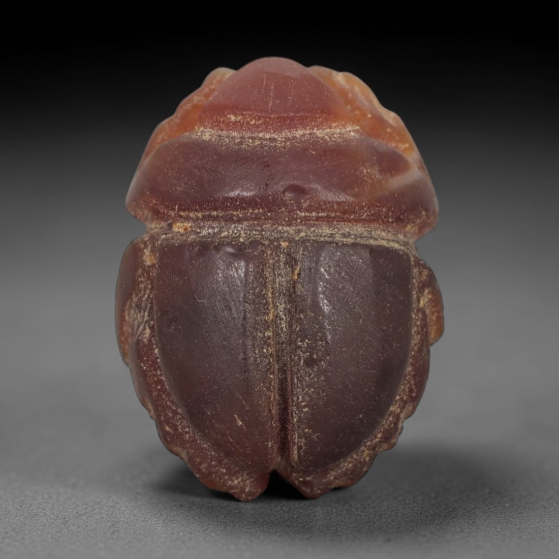 Ancient Carnelian Scarab Amulet - Egyptian Figurine, 36XS: Carved from rich, deep rose-red carnelian with subtle amber undertones and natural mineral variegation, this amulet is formed as a stylized scarab beetle with incised linear detailing to define the ce