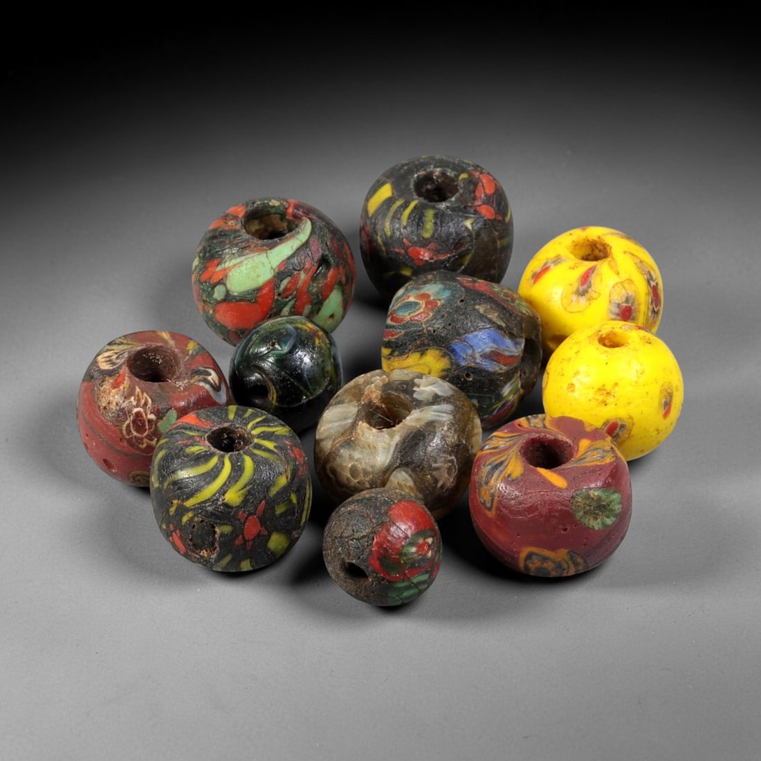 Antique Venetian Glass Trade Beads - Multicolor Set, 60FX: This group of eleven antique Venetian glass trade beads is crafted from hand-worked glass, featuring vibrant layered and mosaic-style patterns in hues of red, green, yellow, black, and blue. Each bead