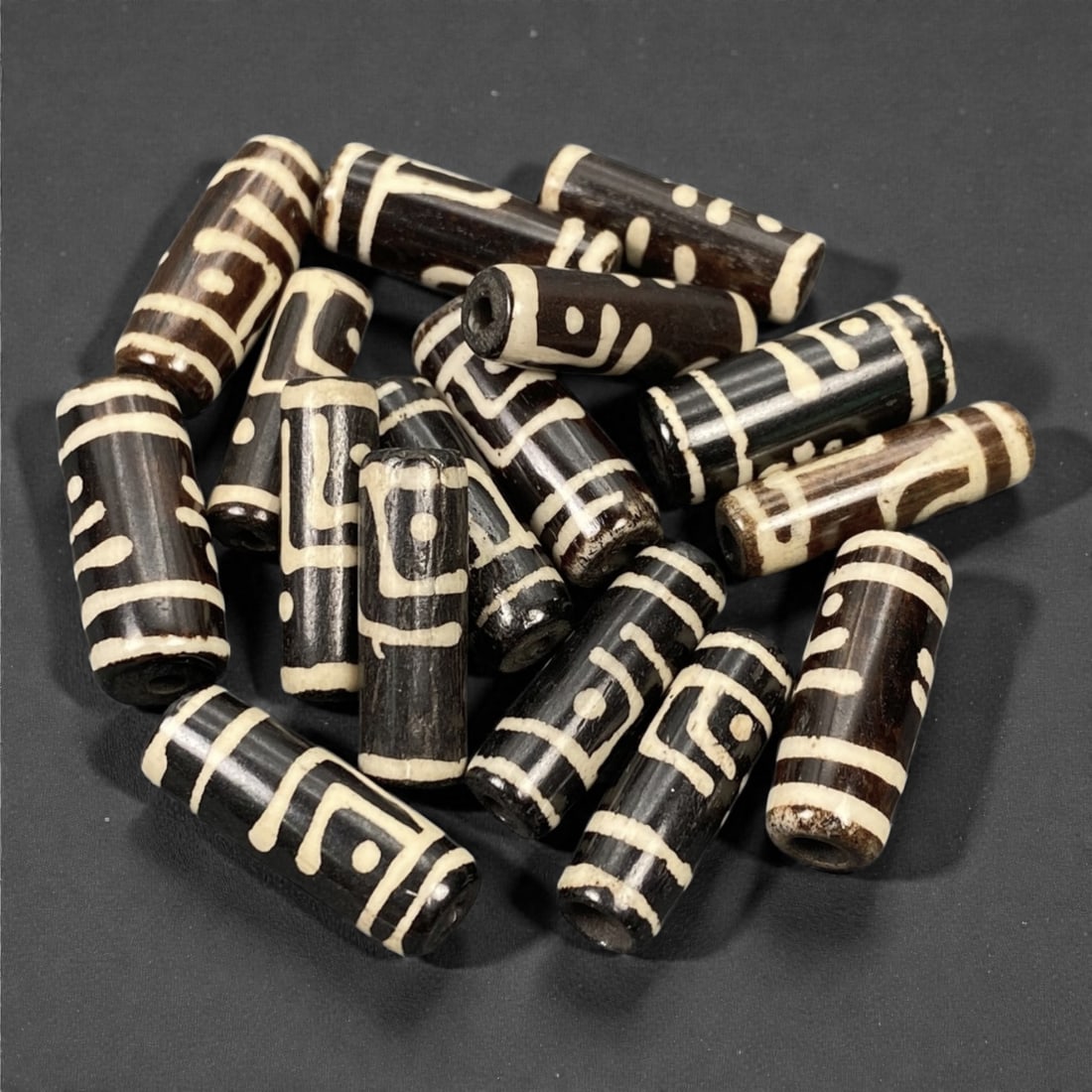 A Tibetan Bone Bead Group, Inlaid Dzi-Style Pattern, 20th Century, 83S: Composed of animal bone, each bead features a cylindrical form with consistent proportions across the group. The surface displays an inlaid decorative scheme emulating traditional Dzi bead iconography