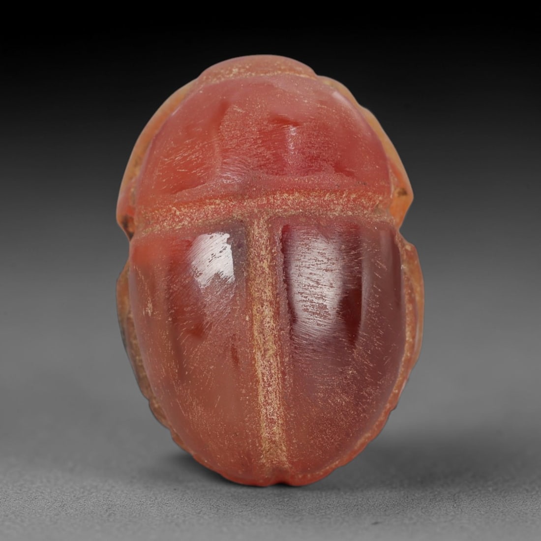 Ancient Carnelian Scarab Amulet - Egyptian Figurine, 27XS: Carved from warm, translucent orange-red carnelian with natural tonal gradients and subtle internal veining, this amulet is formed as a stylized scarab beetle with incised linear detailing to define t