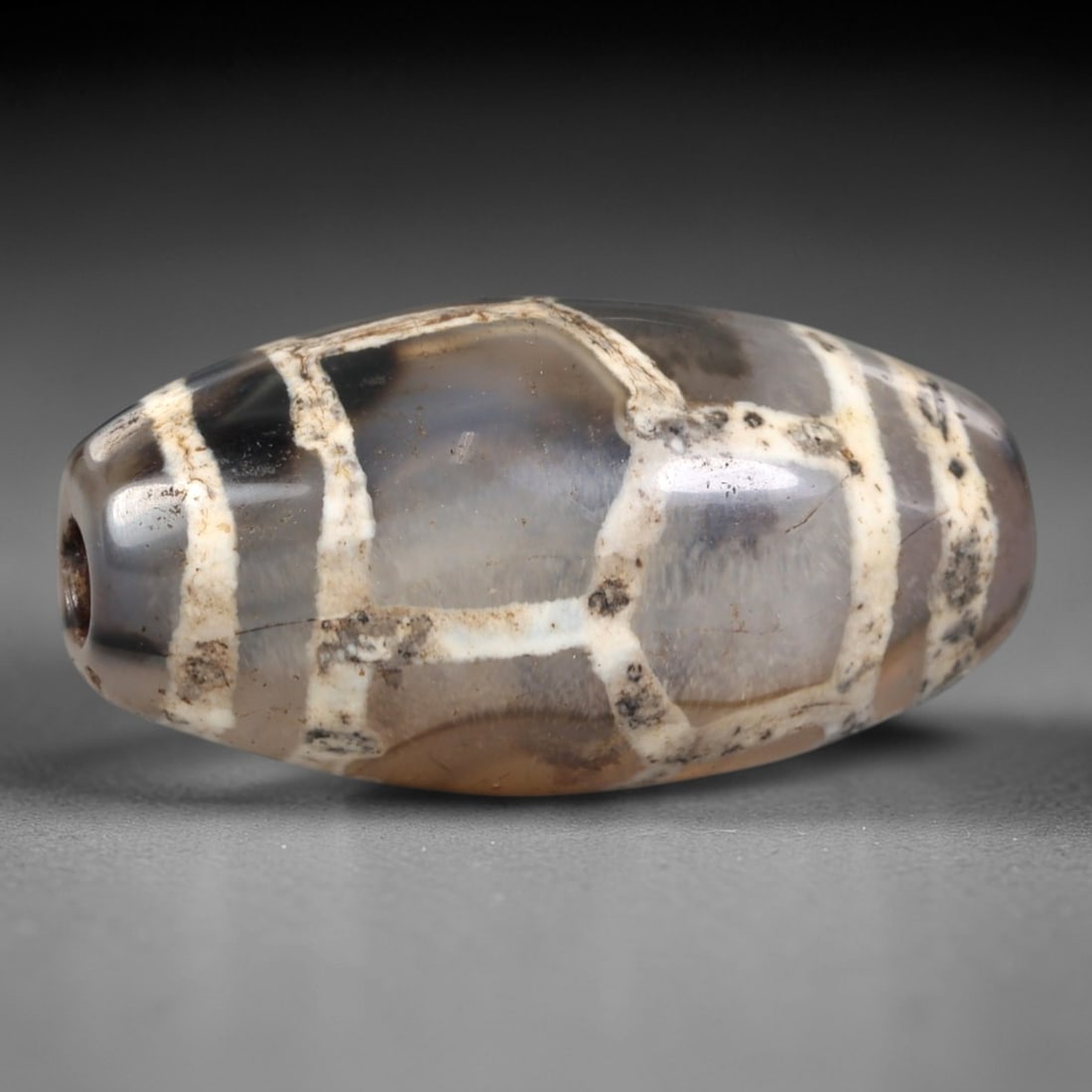 Ancient Agate Etched Dzi Bead - Himalayan Amulet, 92AR: Crafted from translucent agate, this bead displays characteristic etched white linear and geometric patterns applied via traditional Himalayan techniques. The form is a smooth, elongated oval with a c