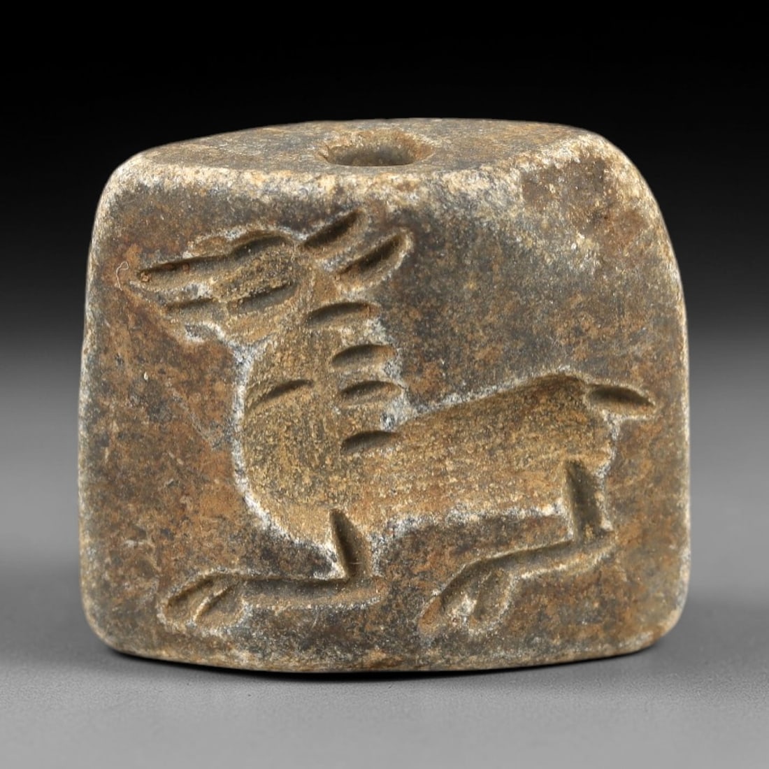 Ancient Schist Double Convex Bead Amulet - Near Eastern Ibex/Gazelle Intaglio, 78AM: Carved from dark gray schist, this 2.3x2cm double convex bead amulet features two complementary intaglio motifs: each side depicts a leaping caprine (likely an ibex or gazelle) with incised linear det