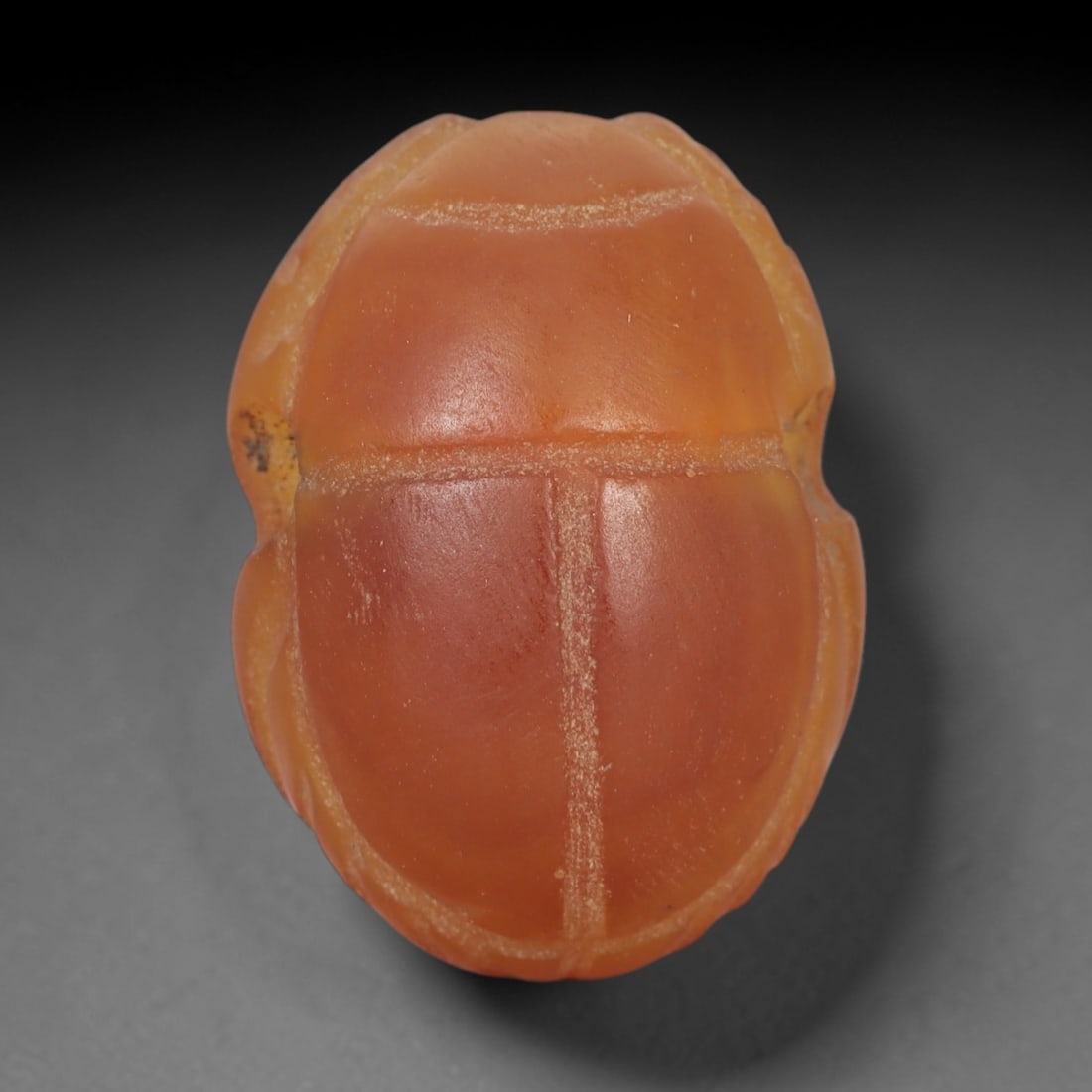Ancient Carnelian Scarab Amulet - Egyptian Figurine, 41XS: Carved from warm, translucent orange carnelian with natural tonal gradients and subtle surface patination, this amulet is formed as a stylized scarab beetle with incised linear detailing to define the