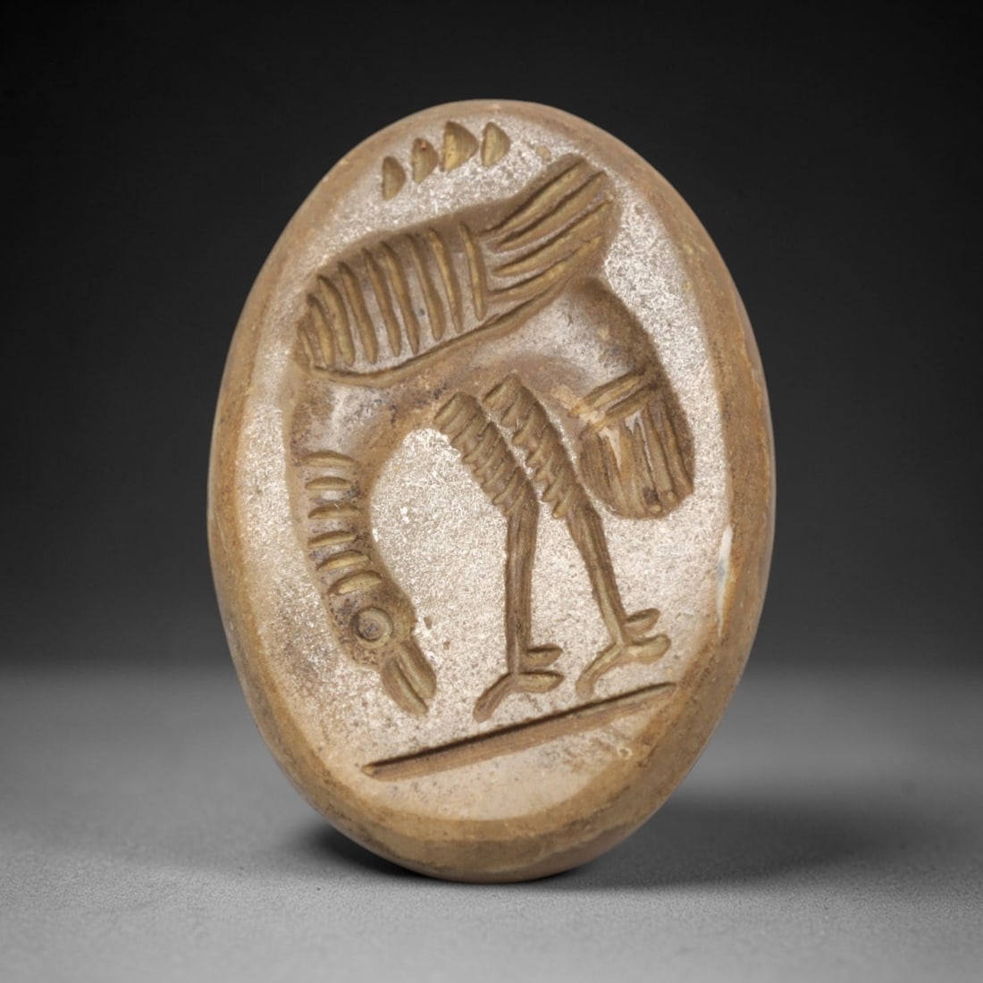 Ancient Agate Intaglio Bead - Near Eastern Bird Motif, 22ZW: Carved from banded agate, this oval intaglio bead features a recessed depiction of a stylized bird in a bent posture, with incised linear detailing to denote feathering, anatomical structure, and a gr