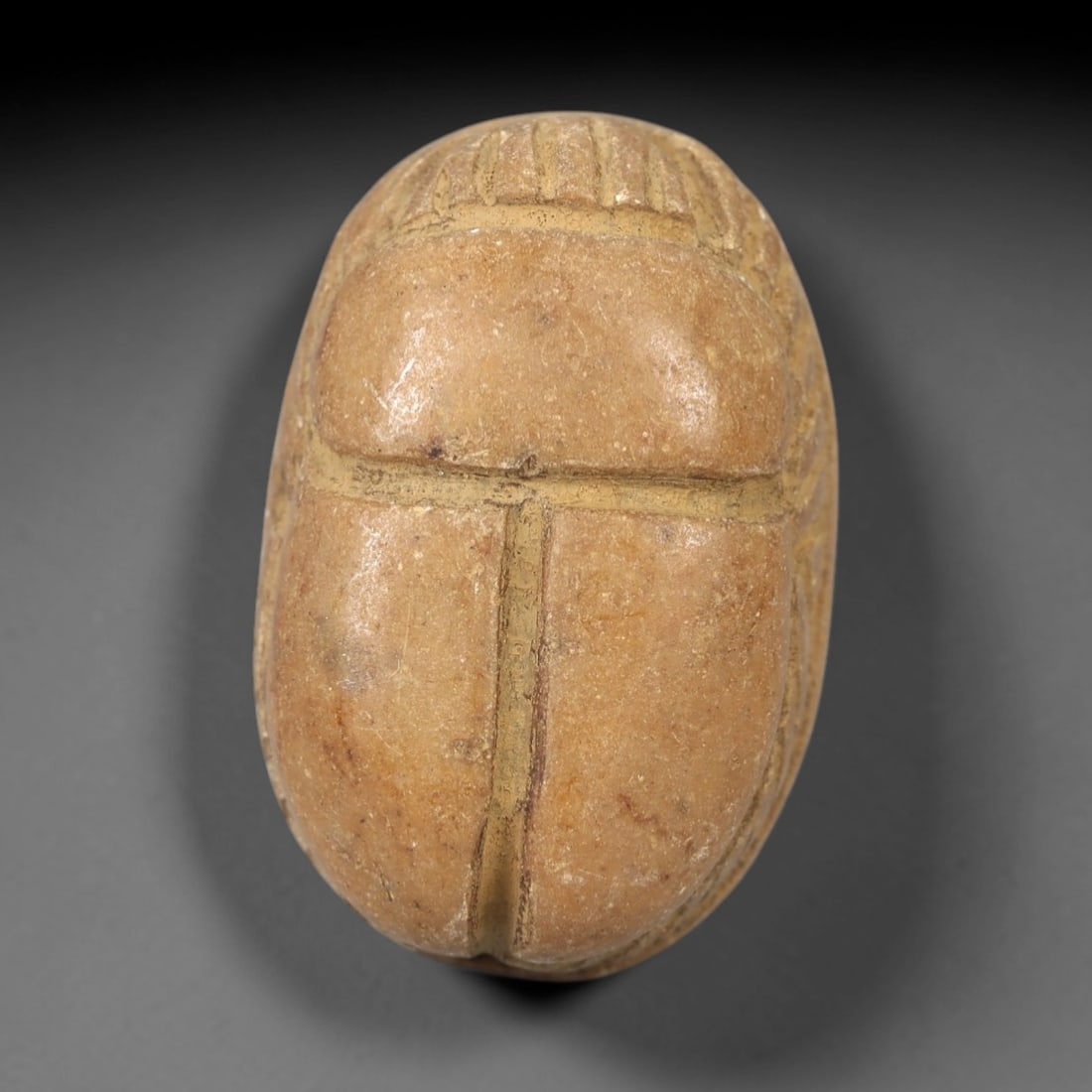 Ancient Egyptian Steatite Scarab - Amulet Figurine, 98AL: This artifact is a carved steatite scarab amulet, crafted from a soft, yellowish-brown steatite (soapstone) with a smooth, slightly weathered surface and warm patina. The dorsal side features bold, si