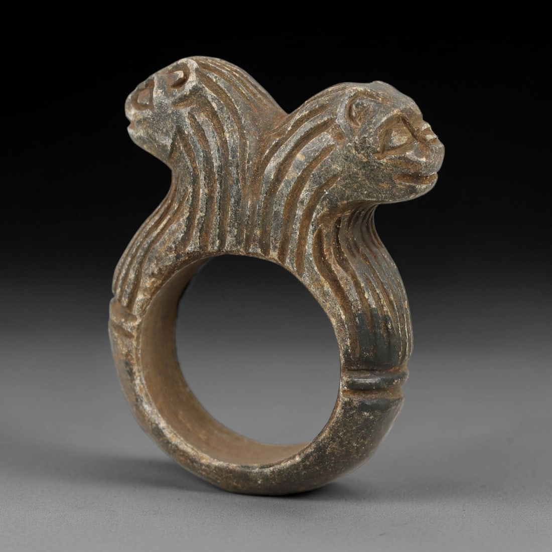Ancient Steatite Achaemenid Ring - Zoomorphic Carving, 97AG: Carved from steatite stone, this ancient Achaemenid ring features a double-protome zoomorphic design with stylized feline heads on either side of the band, a motif characteristic of Achaemenid glyptic