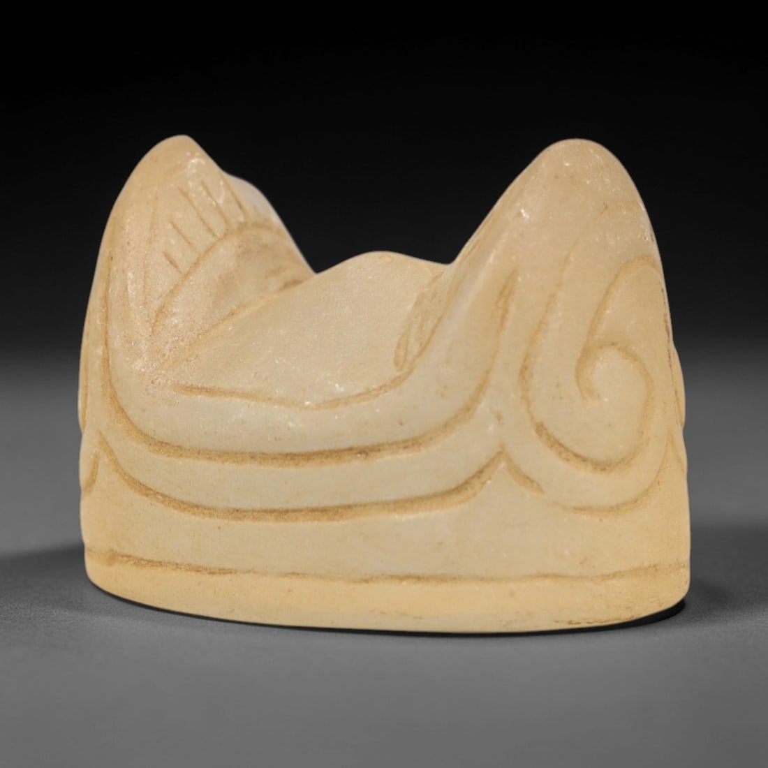 Ancient Glass Medieval Relic - Near Eastern Figurine, 98ZP: This artifact is crafted from translucent ancient glass, formed into a stylized, curved form with raised, symmetrical elements and incised scroll-like decorative motifs. The carving exhibits deliberat