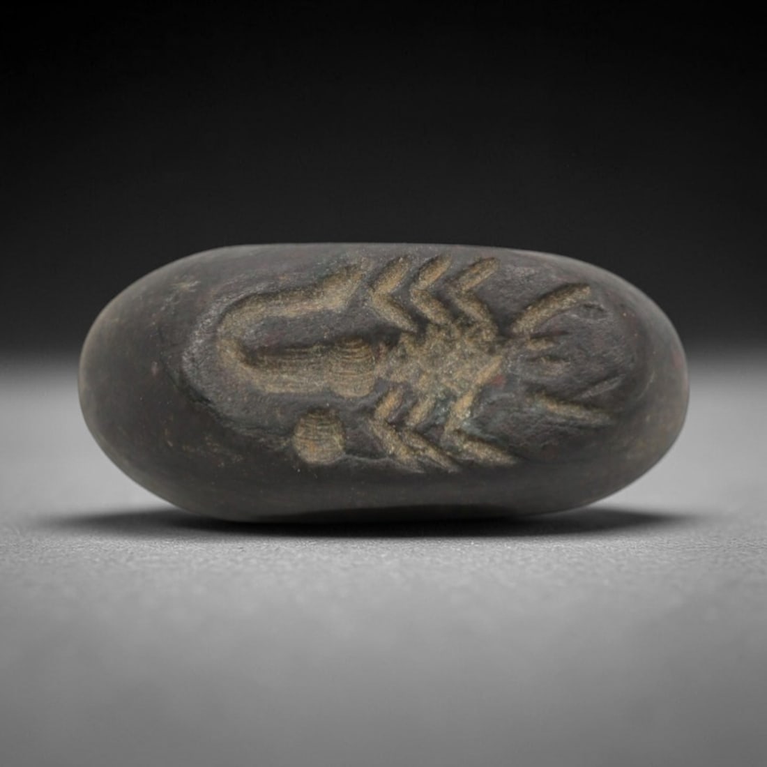 Ancient Stone Hemispherical Stamp Seal - Near Eastern Scorpion Figure, 9ZT: Crafted from dense, fine-grained dark stone, this hemispherical stamp seal bears incised carving of a detailed scorpion figure, with segmented body, raised pincers, and curved tail motifs characterist