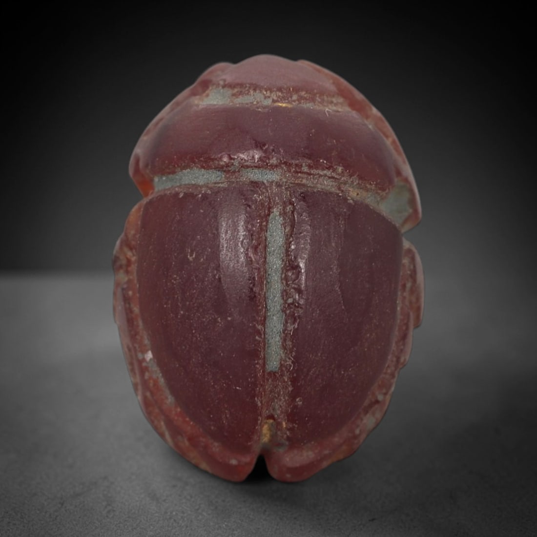 Ancient Carnelian Scarab Amulet - Egyptian Figurine, 32XS: Carved from rich, deep red carnelian with subtle amber undertones and natural mineral variegation, this amulet is formed as a stylized scarab beetle with incised linear detailing to define the central