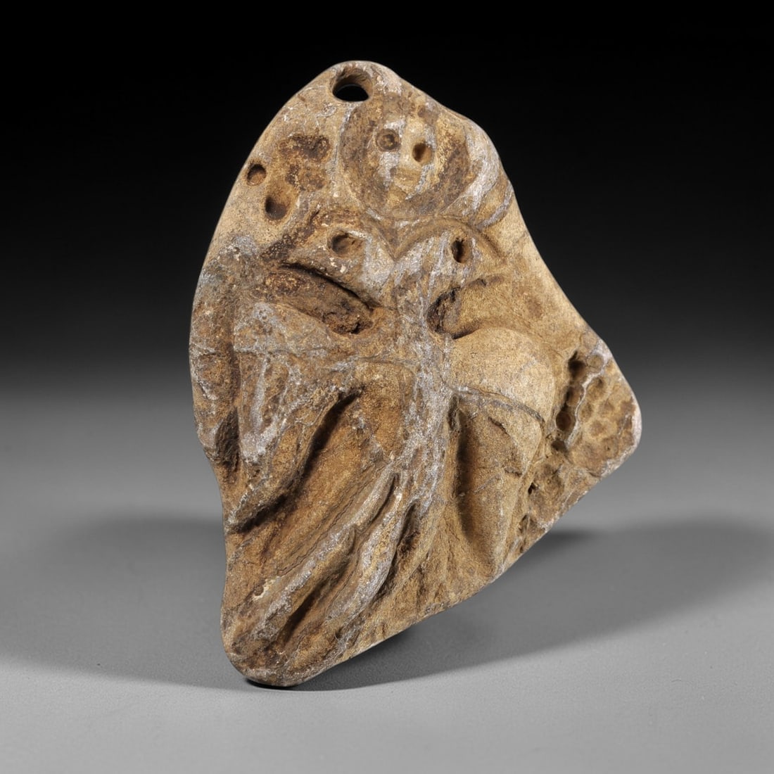 Ancient Stone Double-Headed Bird Amulet - Near Eastern Christian Figurine, 12FY: Carved from a weathered stone, this amulet depicts a double-headed bird in relief, with incised details defining its wings, bodies, and facial features, including multiple perforations for eyes and a