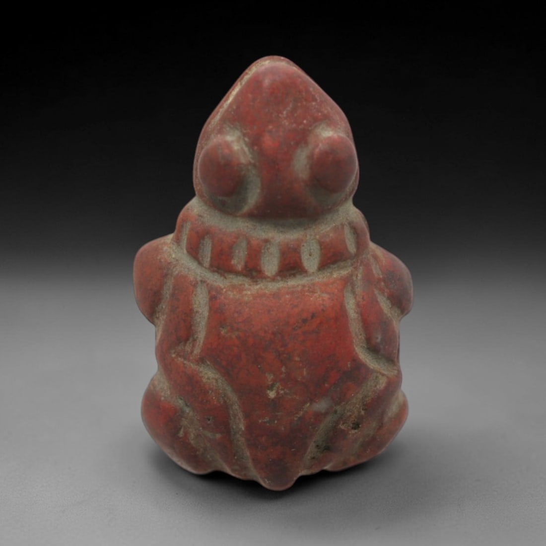 Ancient Red Stone Turtle Amulet - Egyptian Animal Figure, 59ZV: This amulet is carved from a rich red stone, depicting a stylized seated turtle with prominent rounded eyes and incised linear details defining the limbs and a collar-like band around the neck. The fo