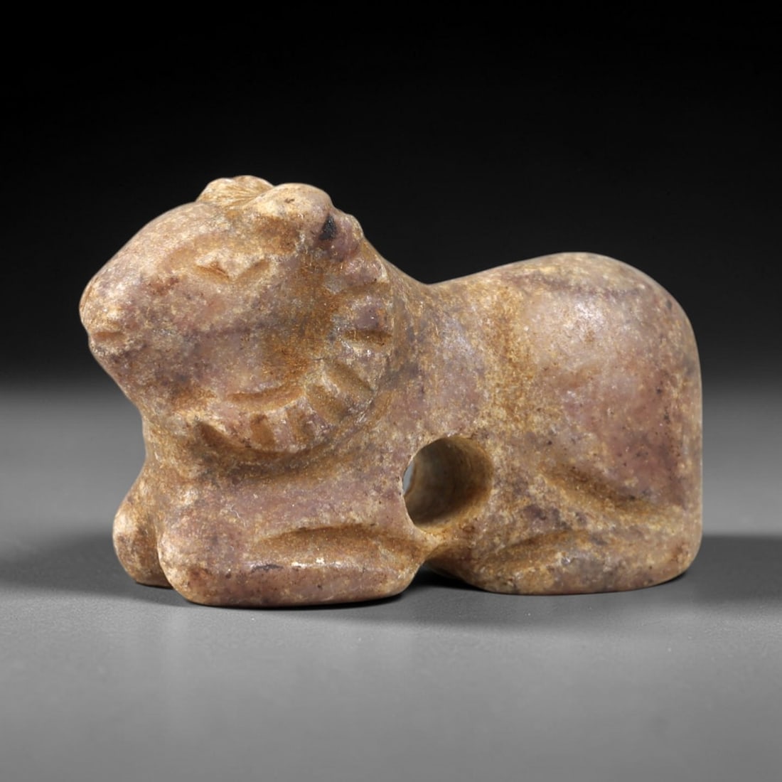 Ancient Stone Ram - Near Eastern Zoomorphic Amulet, 31AS: This zoomorphic amulet is carved from compact stone, displaying a warm, earthy patina consistent with ancient Near Eastern burial contexts. The form depicts a recumbent ram, rendered in a stylized, ro