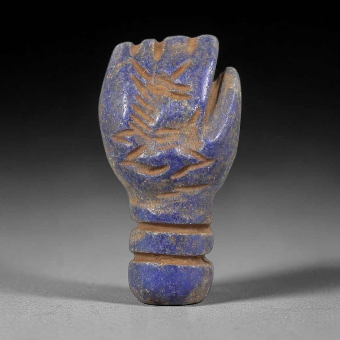 Ancient Lapis Lazuli Fist - Near Eastern Amulet Relic, 19AS: Carved from lapis lazuli, this amulet takes the form of a clenched fist with incised linear detailing across the palm and knuckles, emphasizing the symbolic form. The piece features a distinct, ribbed