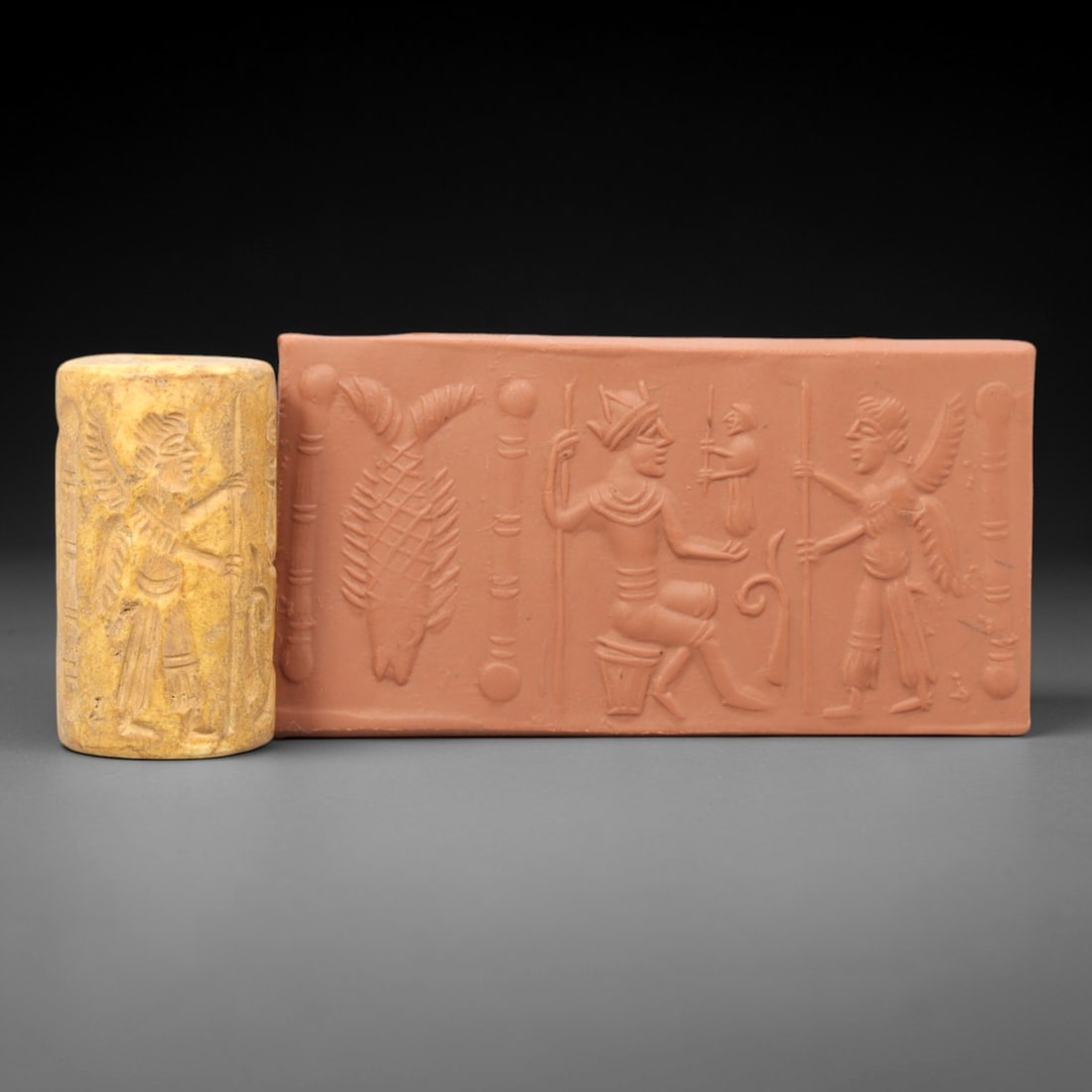 Ancient Steatite Cylinder Seal - Mesopotamian Deity & Attendant, 77ZS: Crafted from creamy steatite, this ancient Mesopotamian cylinder seal presents a finely executed relief scene featuring a crowned central deity seated in repose, attended by a smaller figure and flank