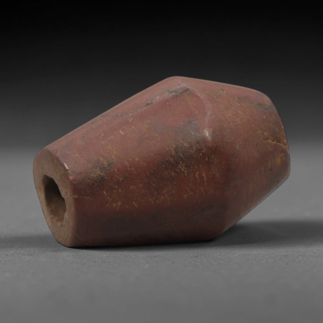 Ancient Stone Bead - Near Eastern Amulet Bead, 55XR: Carved from reddish-brown stone, this faceted bead features a central axial perforation for threading, consistent with Ancient Near Eastern bead craftsmanship of the Iron Age. The angular, multi-sided