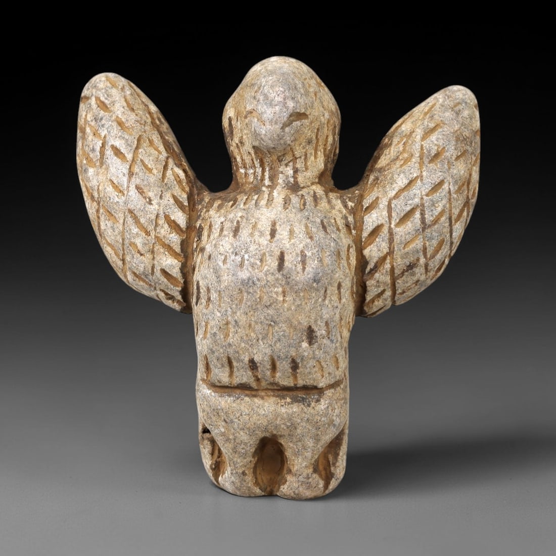 Ancient Stone Vulture Amulet - Near Eastern Avian Figure, 56AM: This vulture amulet is carved from light speckled stone, depicting a stylized vulture with outstretched wings and a compact, rounded body. The piece features incised linear and stippled detailing to d