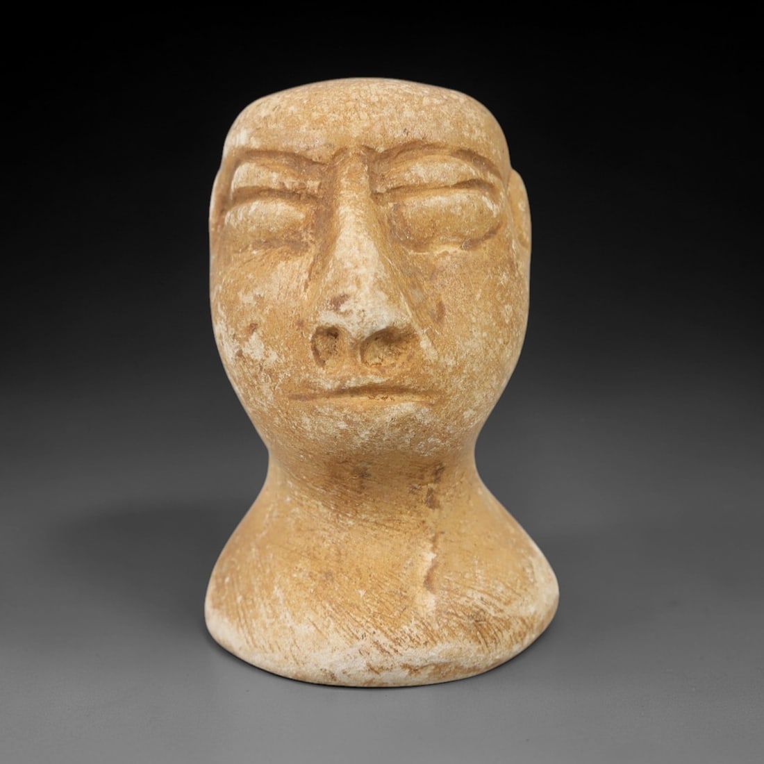 Ancient Limestone Bust - Bactrian Idol Head, 29AH: Carved from limestone, this ancient Bactrian idol head is a complete bust featuring a stylized human facial form with detailed eye sockets and subtle facial features typical of Bactrian artistic tradi