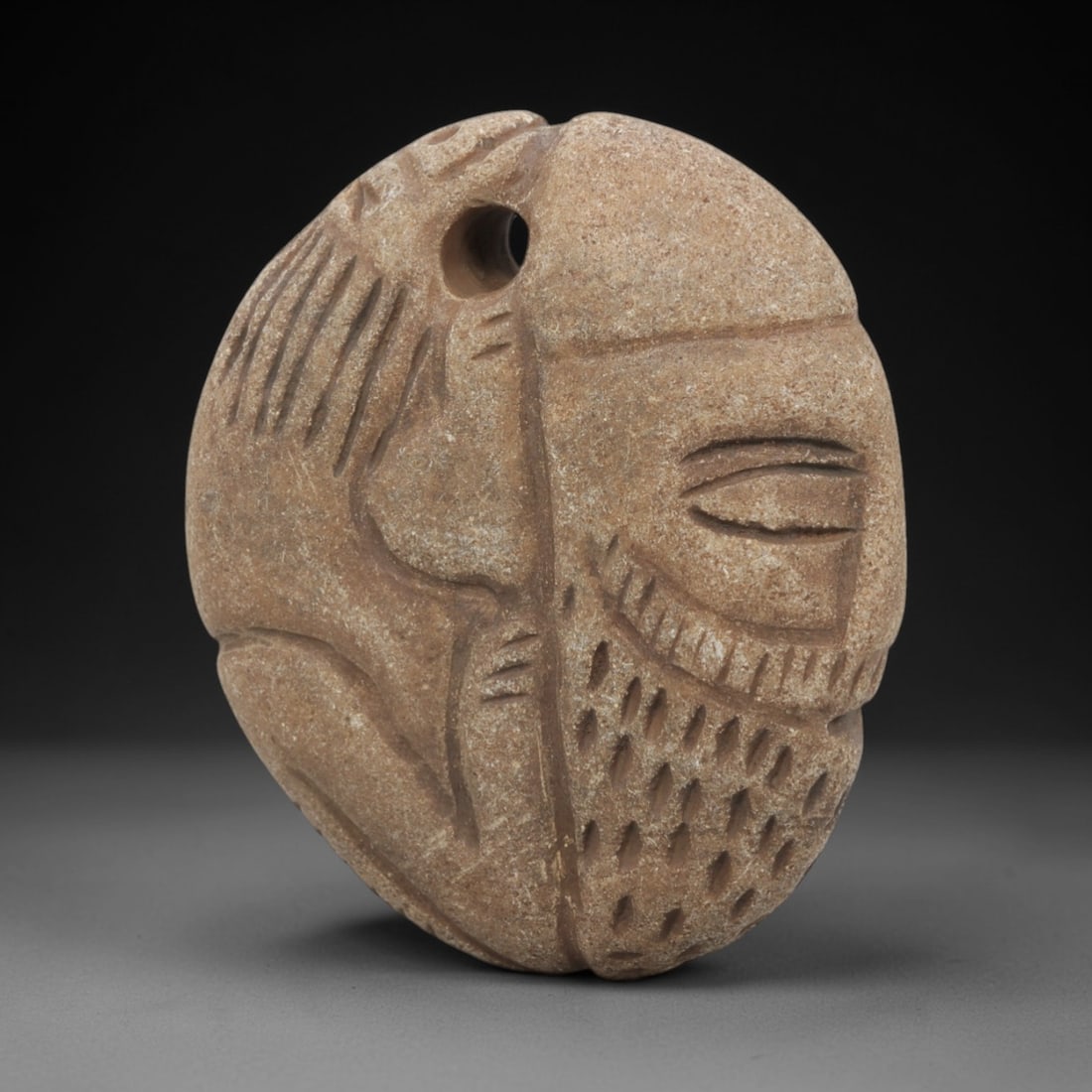 Ancient Stone Amulet - Near Eastern Human-Animal Figurine, 40FX: Carved from a fine-grained, tan-colored stone, this amulet is divided into two distinct iconographic sections: the left depicts a stylized animal form with incised linear details defining its limbs an