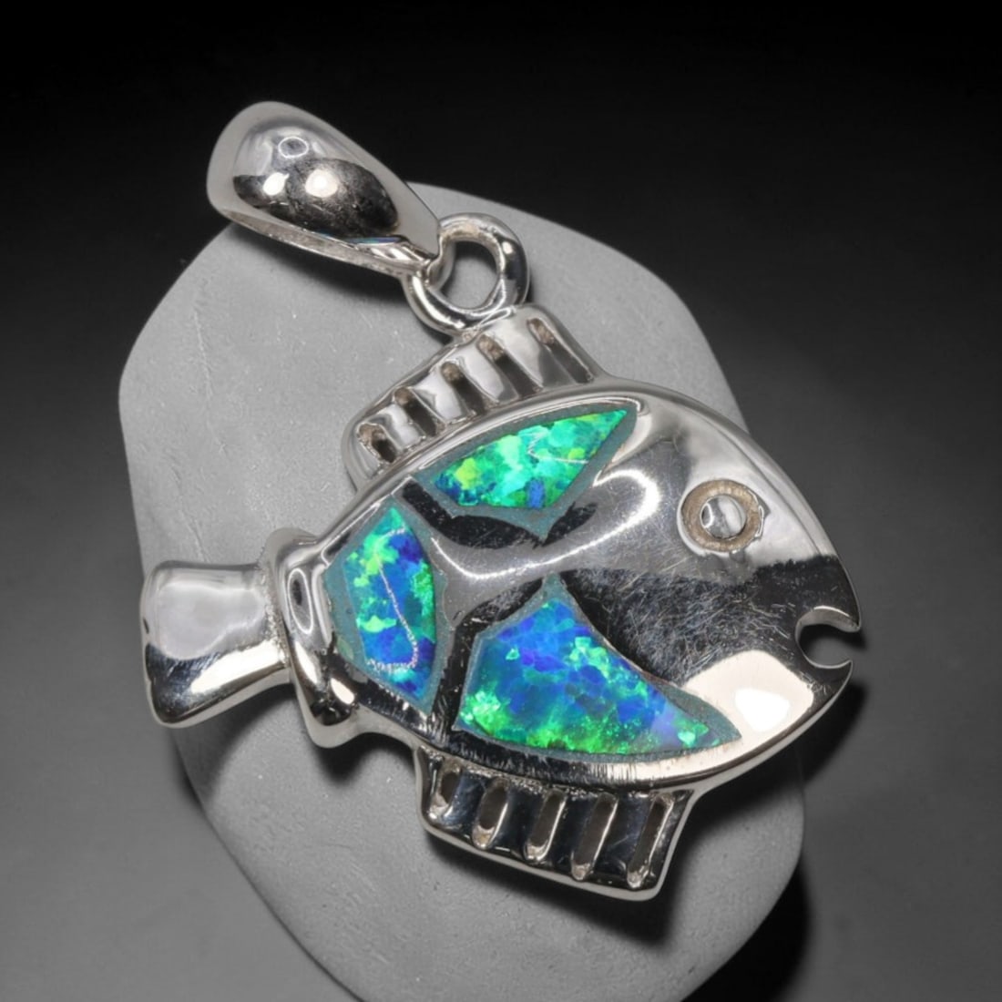 3.37g 925 Sterling Silver Fish Pendant - Simulated Opal, 11D: Crafted from stamped 925 sterling silver, this pendant depicts a stylized tropical fish in polished openwork form. The fish's body is inlaid with three segments of simulated opal, exhibiting vivid iri
