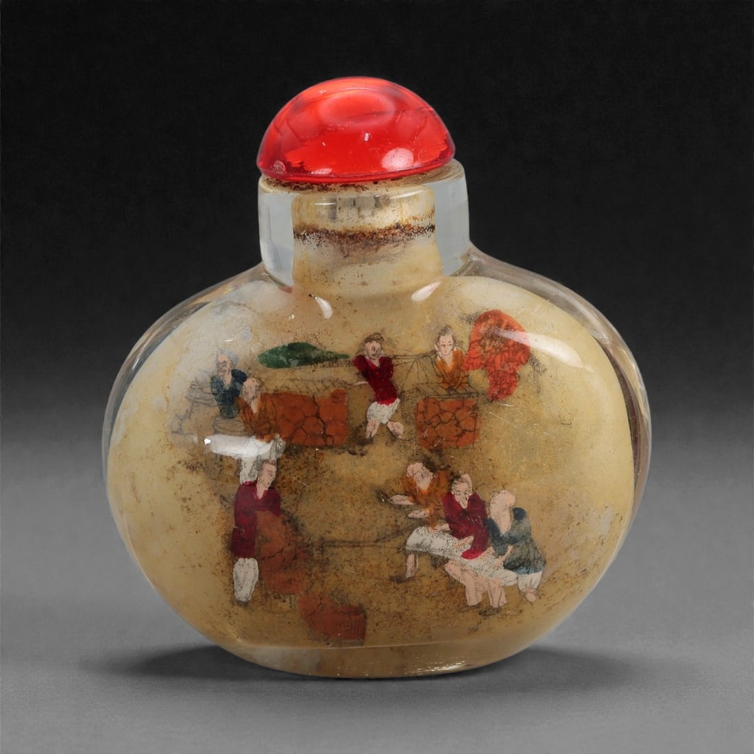 A Chinese Glass Snuff Bottle with Inside-Painted Figural Scenes, 20th Century, 62FD: Formed from clear glass with a rounded flattened body, gently curved shoulders, and a short cylindrical neck, fitted with a domed red stopper. The interior is hand-painted in polychrome with figural s