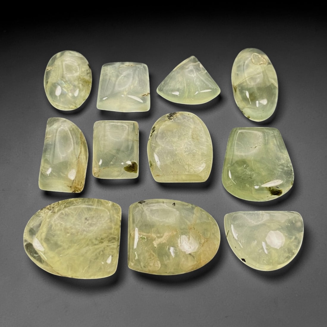 196 Carats Pale Green Prehnite Cabochon Parcel - Natural Malagasy Stones - 1.3-2.2cm, 69ZJ: This curated parcel of loose prehnite cabochons captivates with a soft, translucent pale green hue, each stone radiating a gentle, milky glow that evokes the quiet beauty of a forest stream. The inter