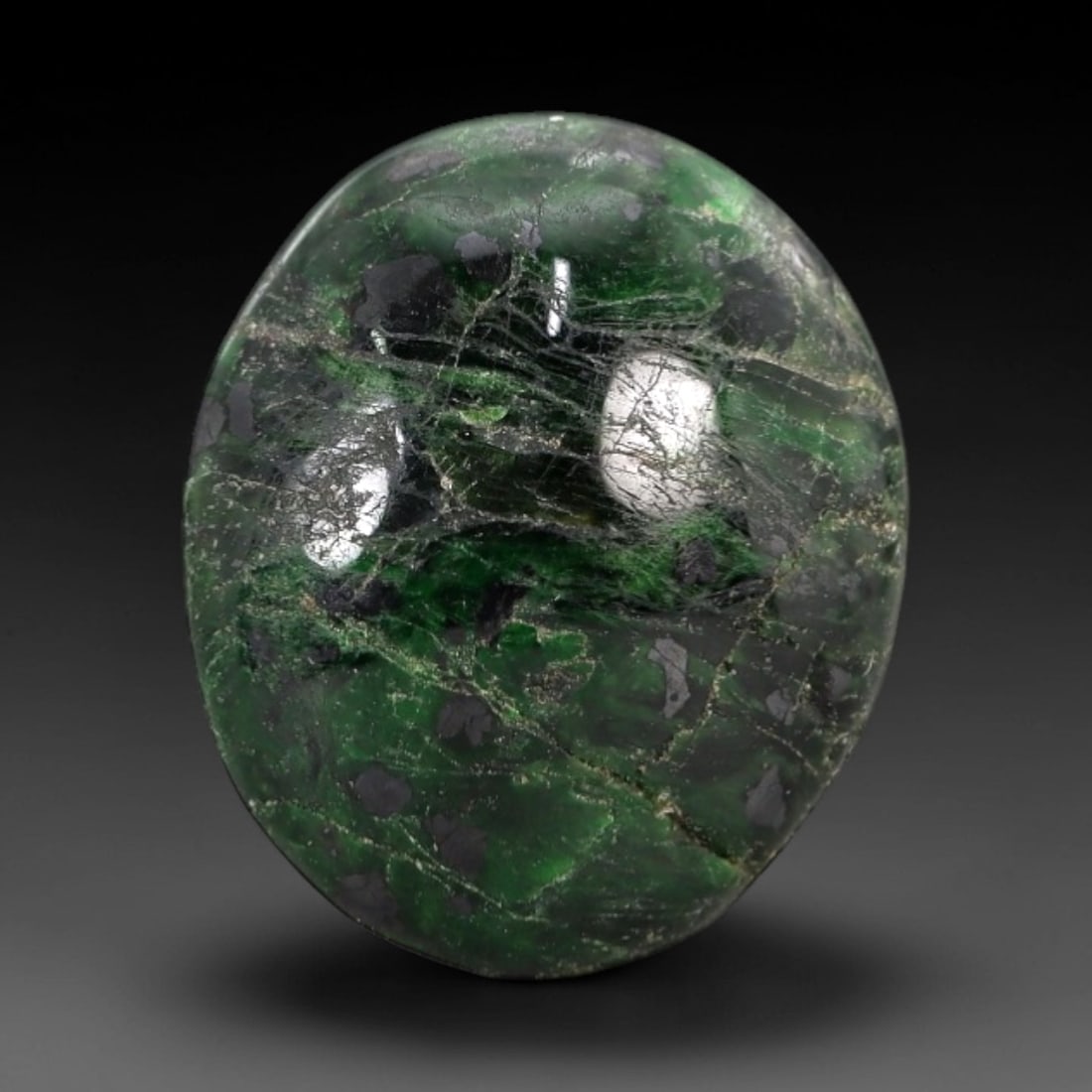 9.03 Carats Deep Green Maw Sit Sit Jade Cabochon - Natural Burmese Stone, 13AB: This maw sit sit jade cabochon is fashioned into an oval, domed form with a highly polished surface. The material exhibits a deep, saturated green matrix, interspersed with distinct, darker green and