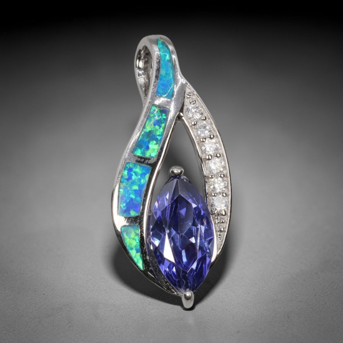 4.27g 925 Sterling Silver Pendant - Simulated Opal Tanzanite, 7D: Crafted from stamped 925 sterling silver, this pendant features a fluid, teardrop-shaped openwork design. Four rectangular segments of simulated opal are inlaid along one curved edge, exhibiting vivid