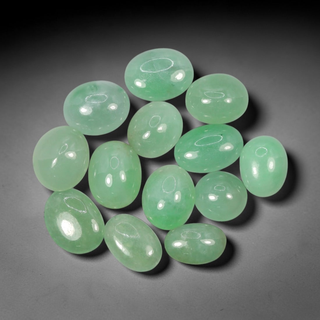 Natural Type A Jadeite Jade - Loose Cabochon Gemstone, 1AP: Crafted from natural Type A jadeite jade, these thirteen cabochons display a translucent pale green hue with subtle tonal variations inherent to the material. Each stone is cut en cabochon with a smoo
